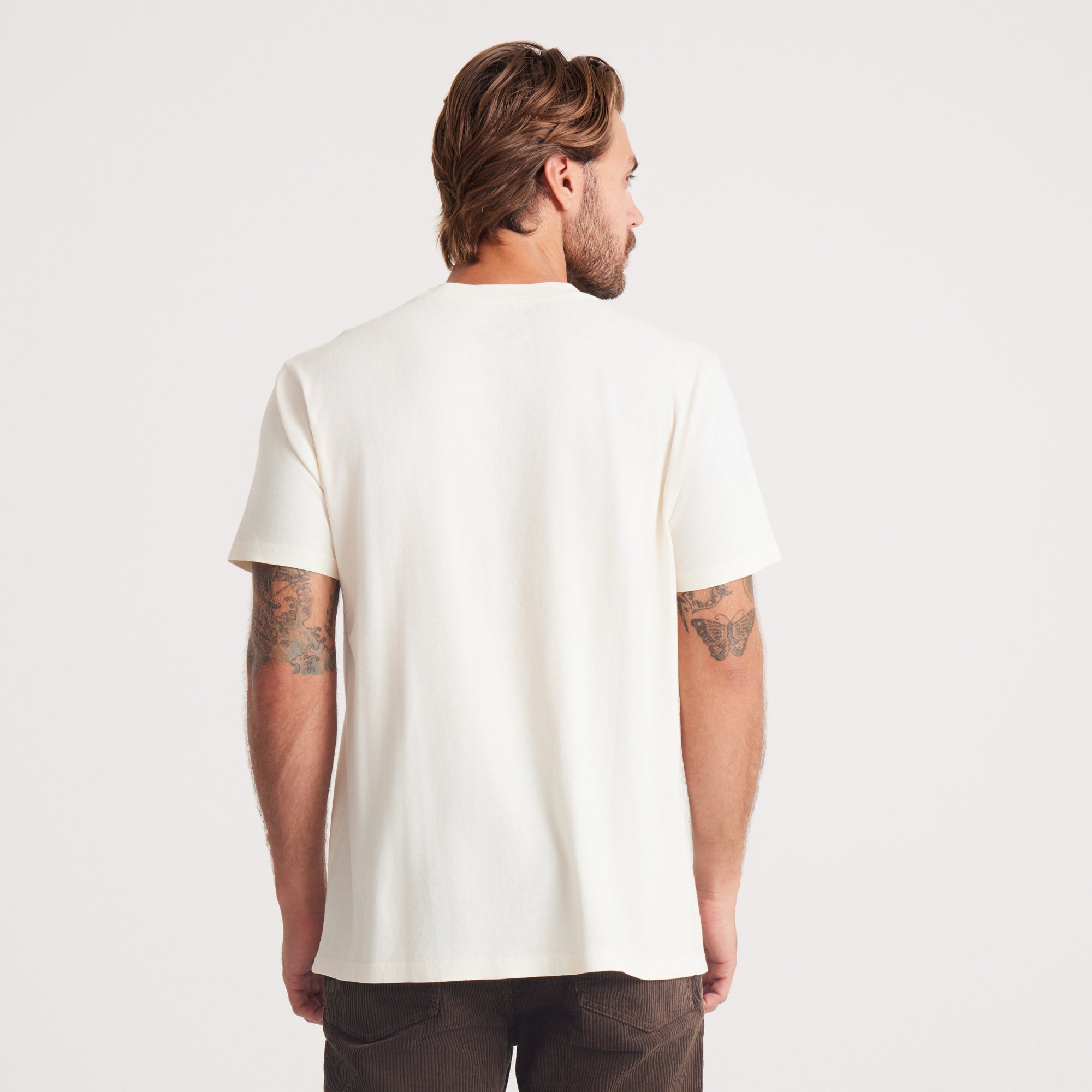 The back view of the man in a white Roark t-shirt, highlighting a relaxed fit, perfect for everyday wear.