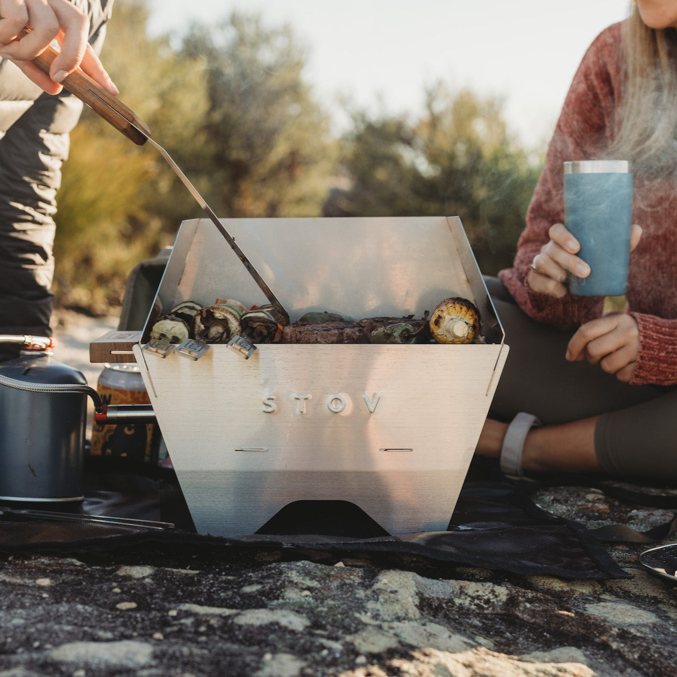Two people cooking on compact STOV BBQ while outdoors
