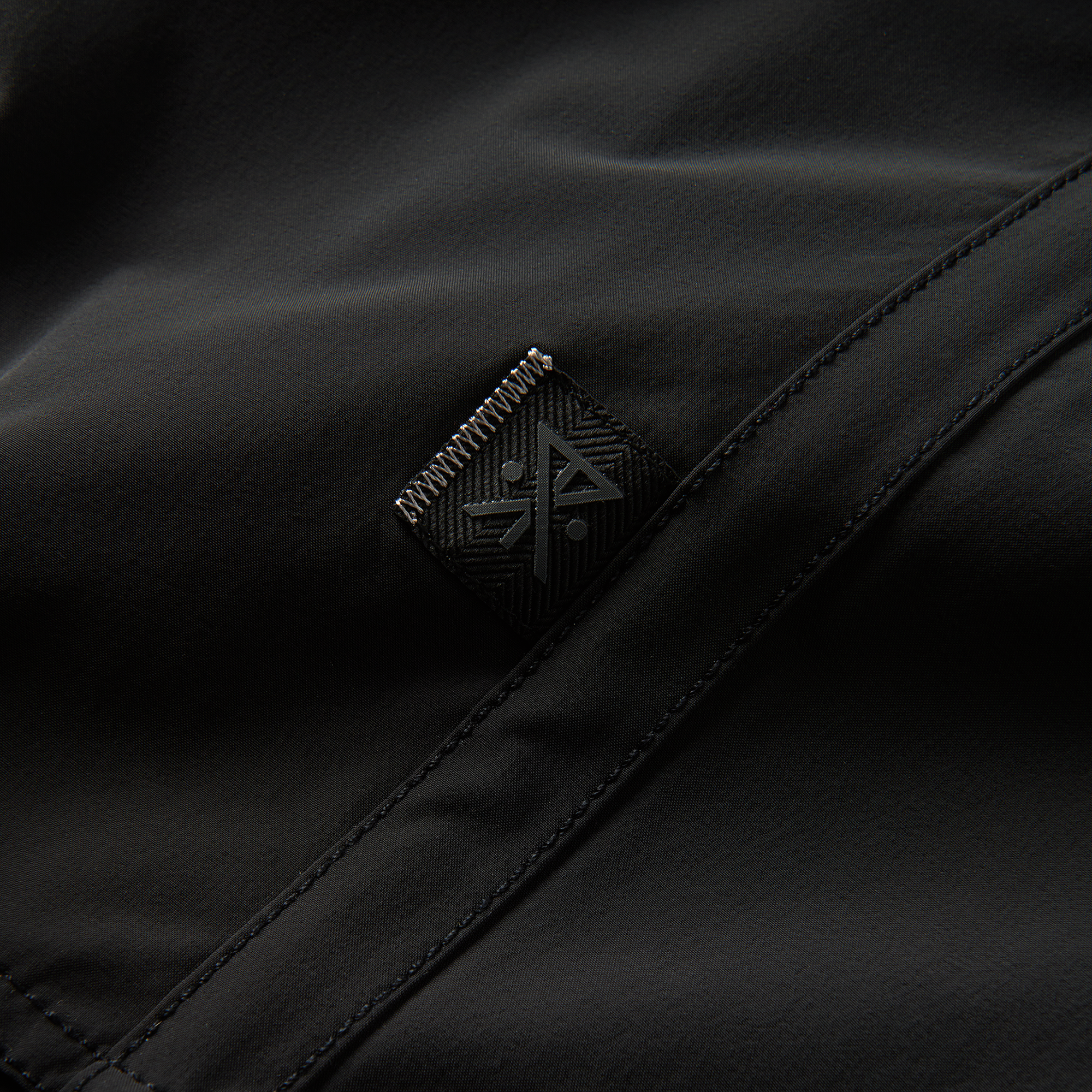 Zoomed-in view of the Roark logo and fabric detail on black boardshorts, highlighting premium craftsmanship and durability