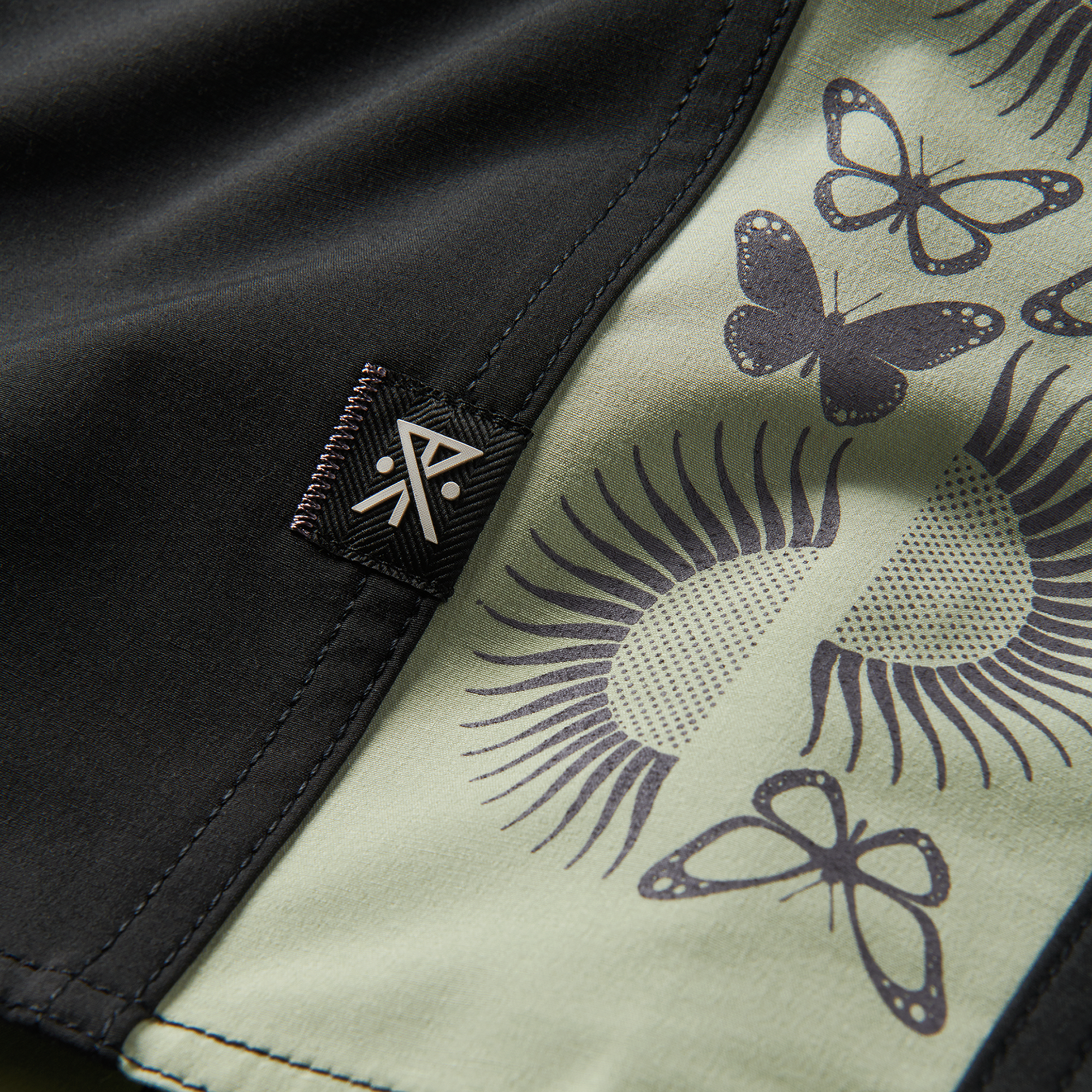 Close-up of butterfly and sun pattern details on black shorts for a bold, artistic vibe. Explore unique activewear style now!