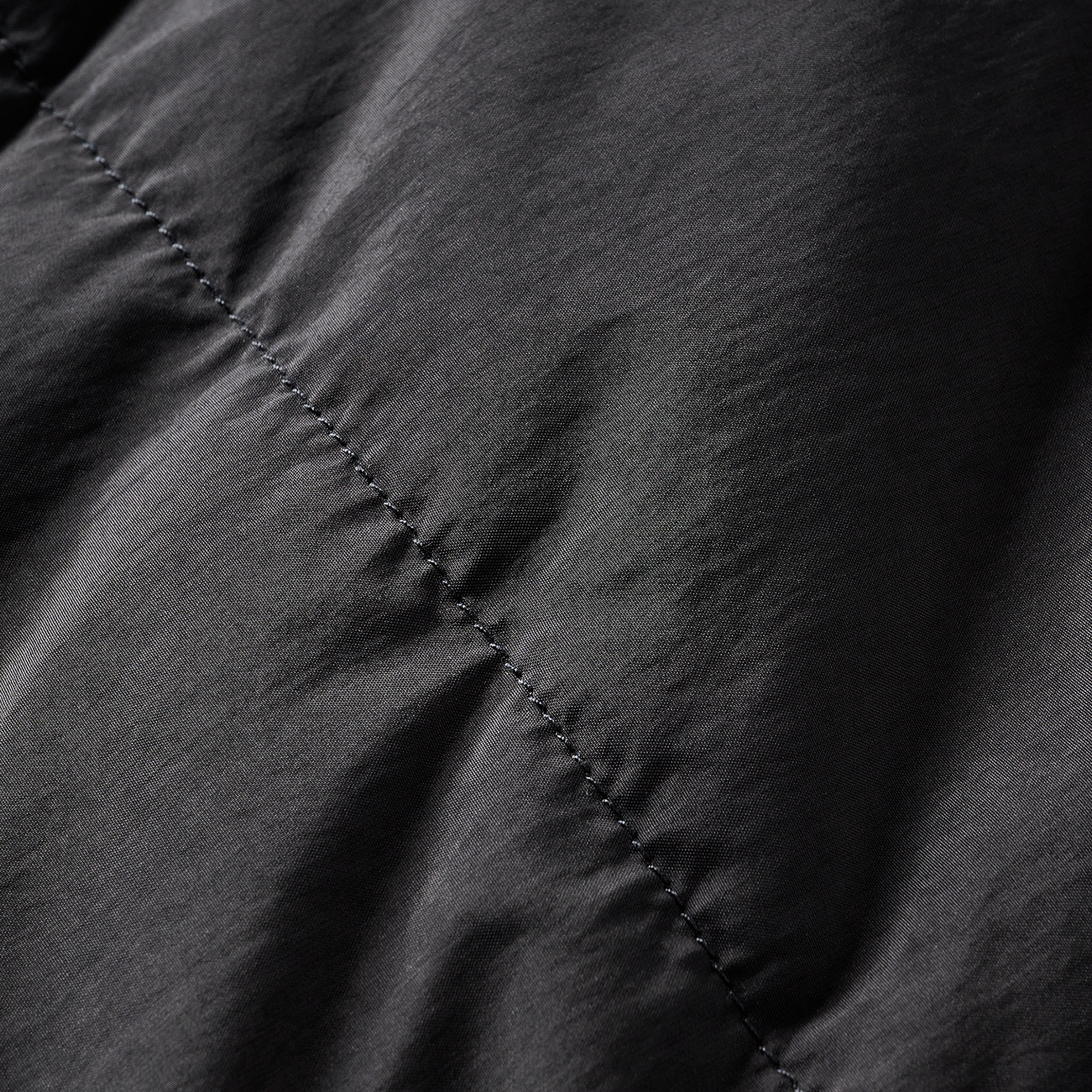 Detail view of the stitching on the black section of the puffer jacket, highlighting premium craftsmanship and durability.