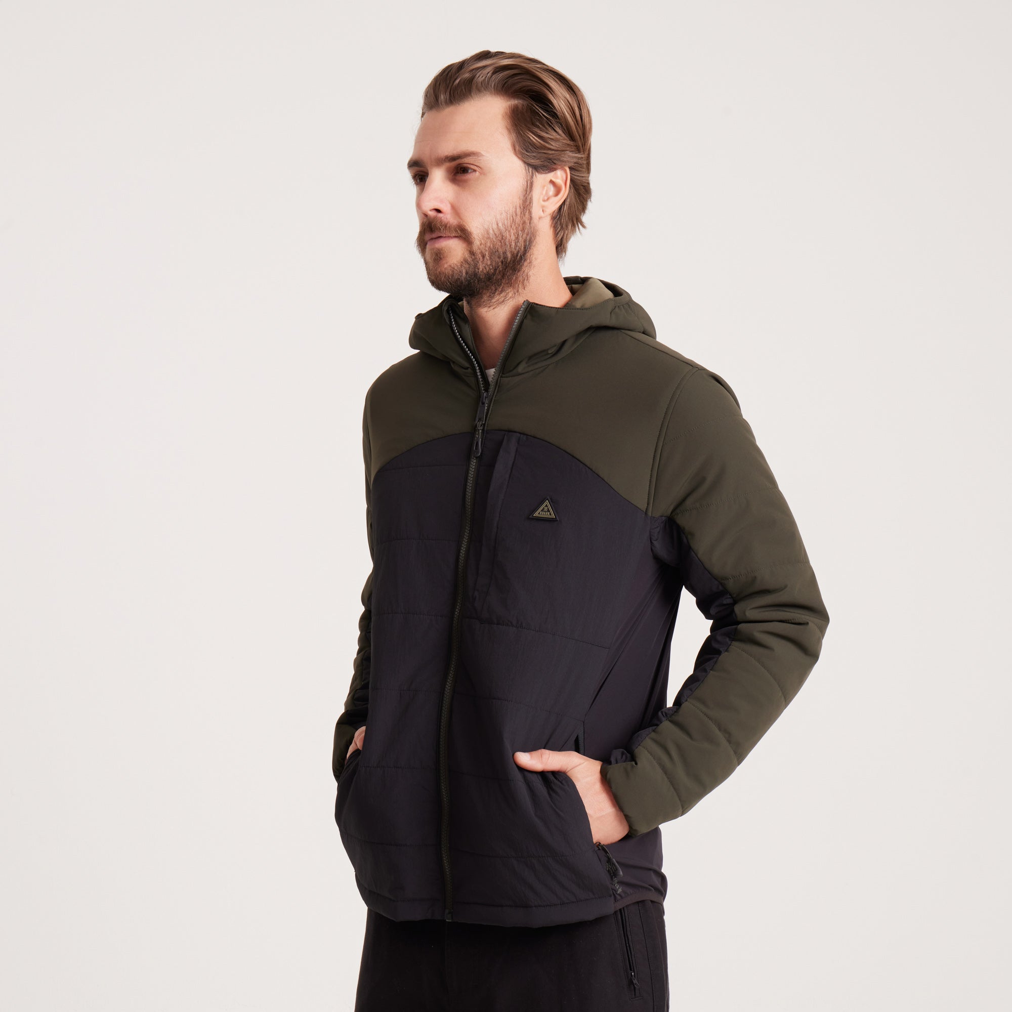 Man showing the inner lining of a green and black hooded jacket, highlighting its warm and durable construction.