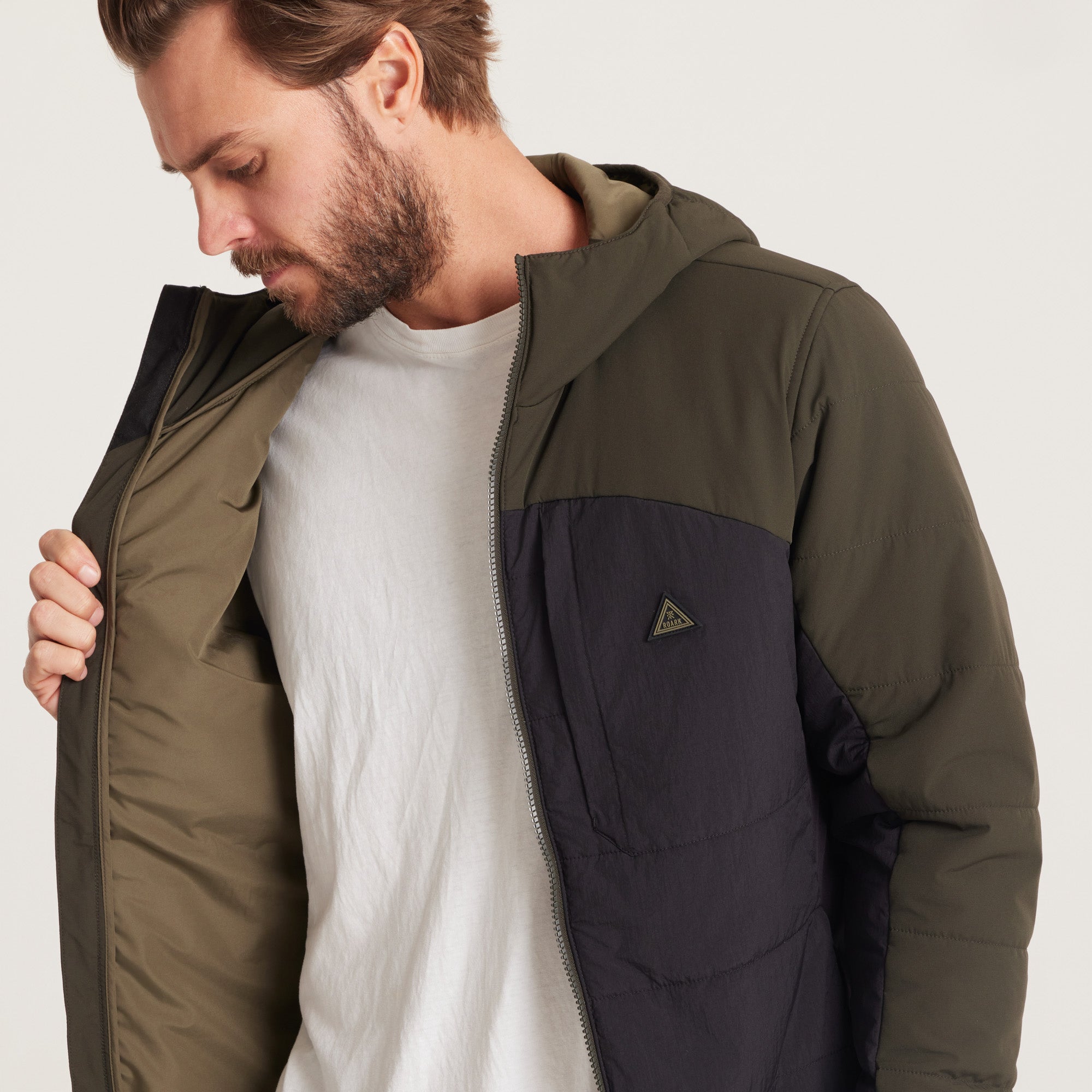 Detailed view of the zipper and stitching on a green and black hooded jacket, highlighting durable materials.