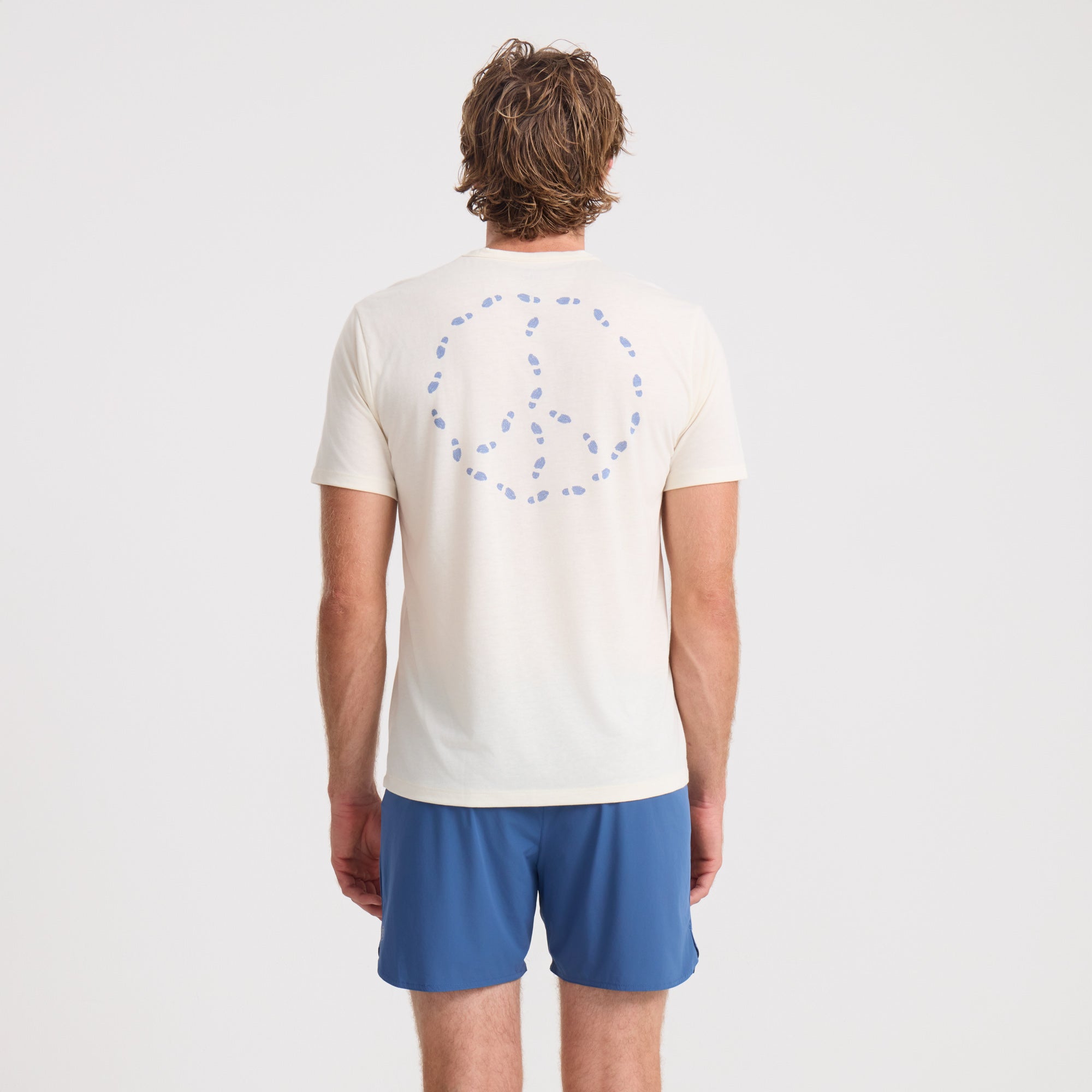 Active person preparing for an outdoor adventure, wearing a breathable shirt and versatile Bermuda shorts from Roark, ready for both comfort and action.