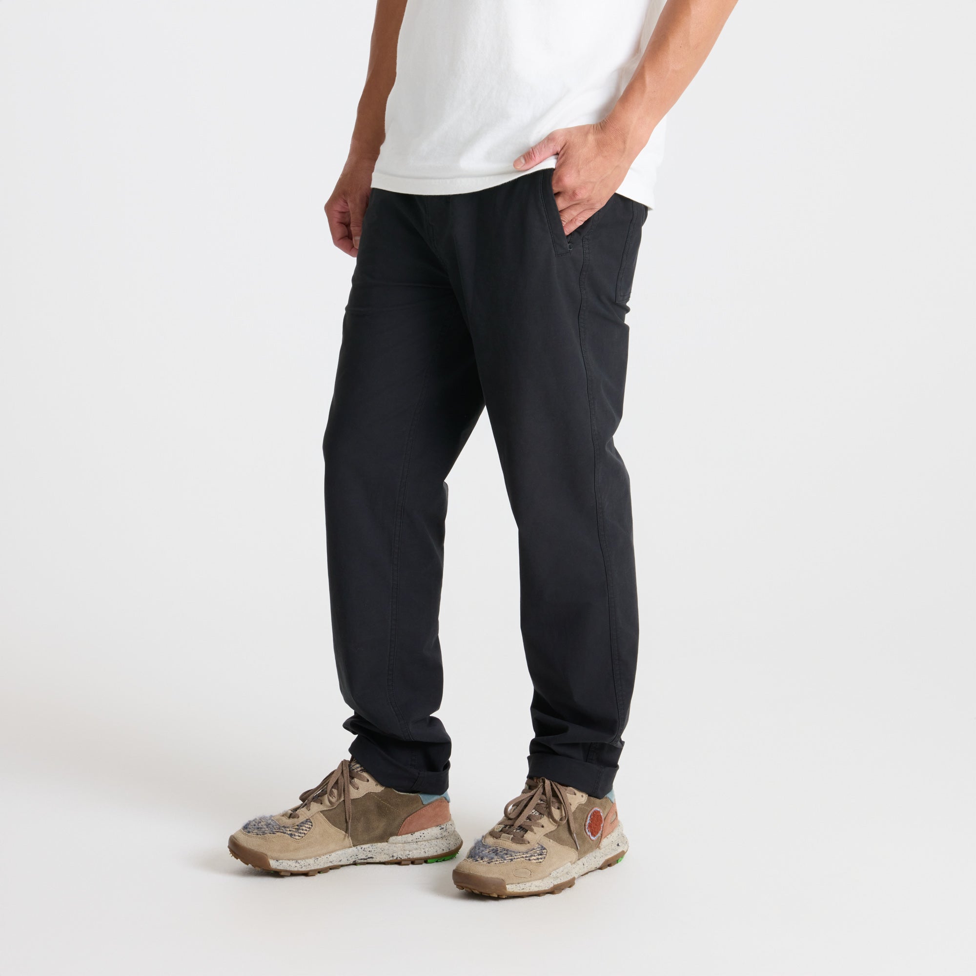 Group of adventurers walking through rugged terrain wearing durable Roark active pants and walking shoes, embodying the spirit of exploration.