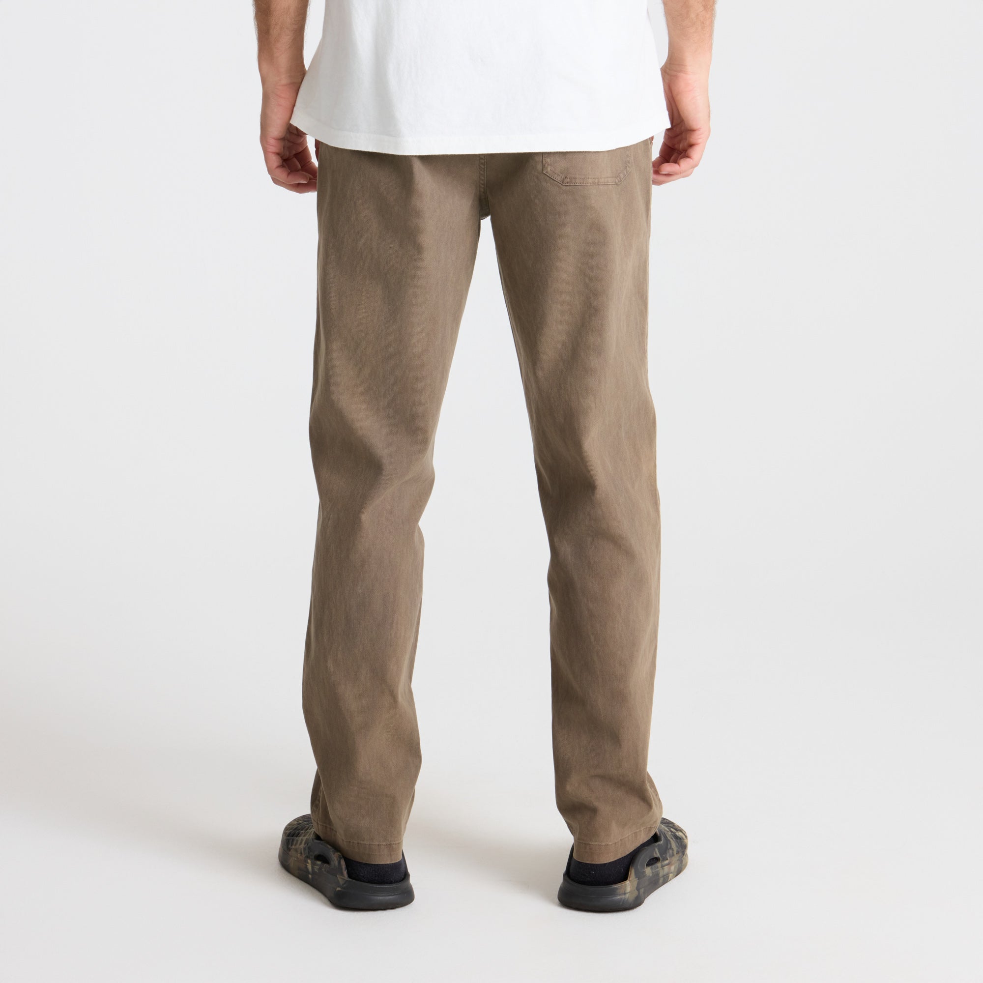 Close-up of the detailed craftsmanship on Roark's khaki pants featuring a pocket, ideal for adventure travel, paired with durable walking shoes.