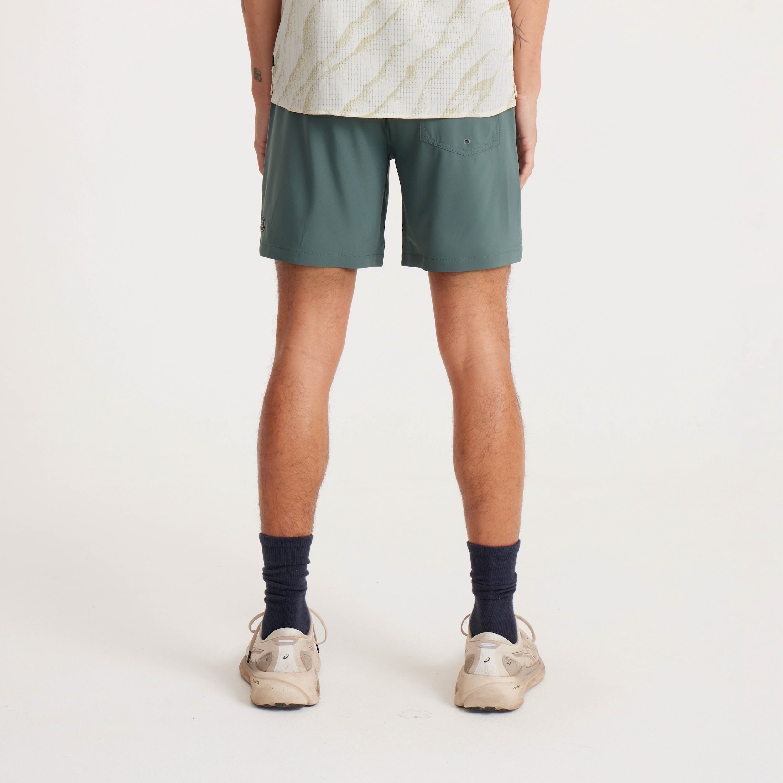 Rear view of green active shorts paired with neutral sneakers, designed for outdoor and athletic activities.
