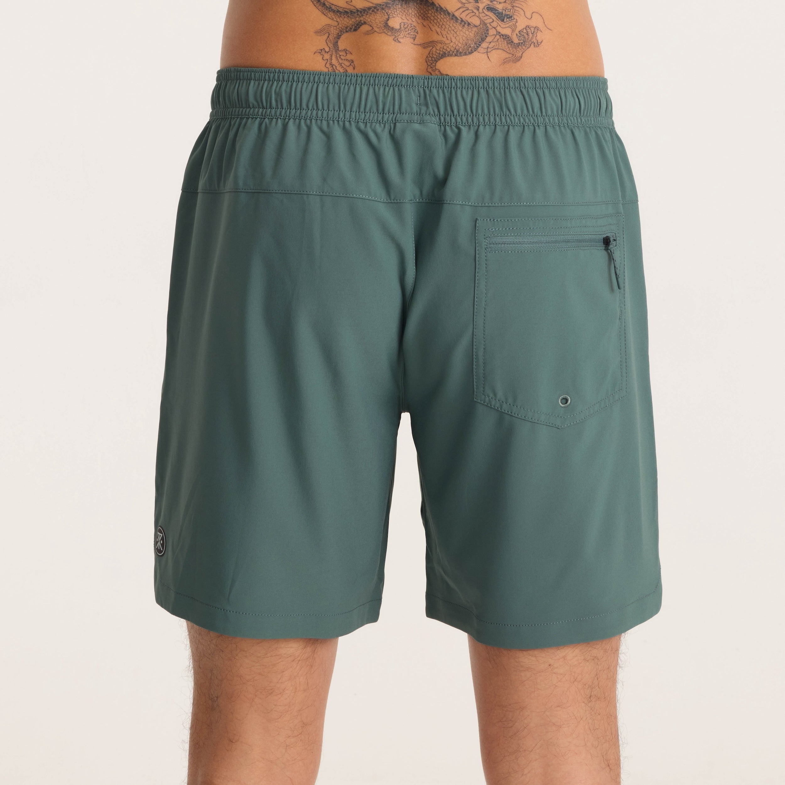 Back view of green men's active shorts with zippered pocket and elastic waistband for outdoor adventures.