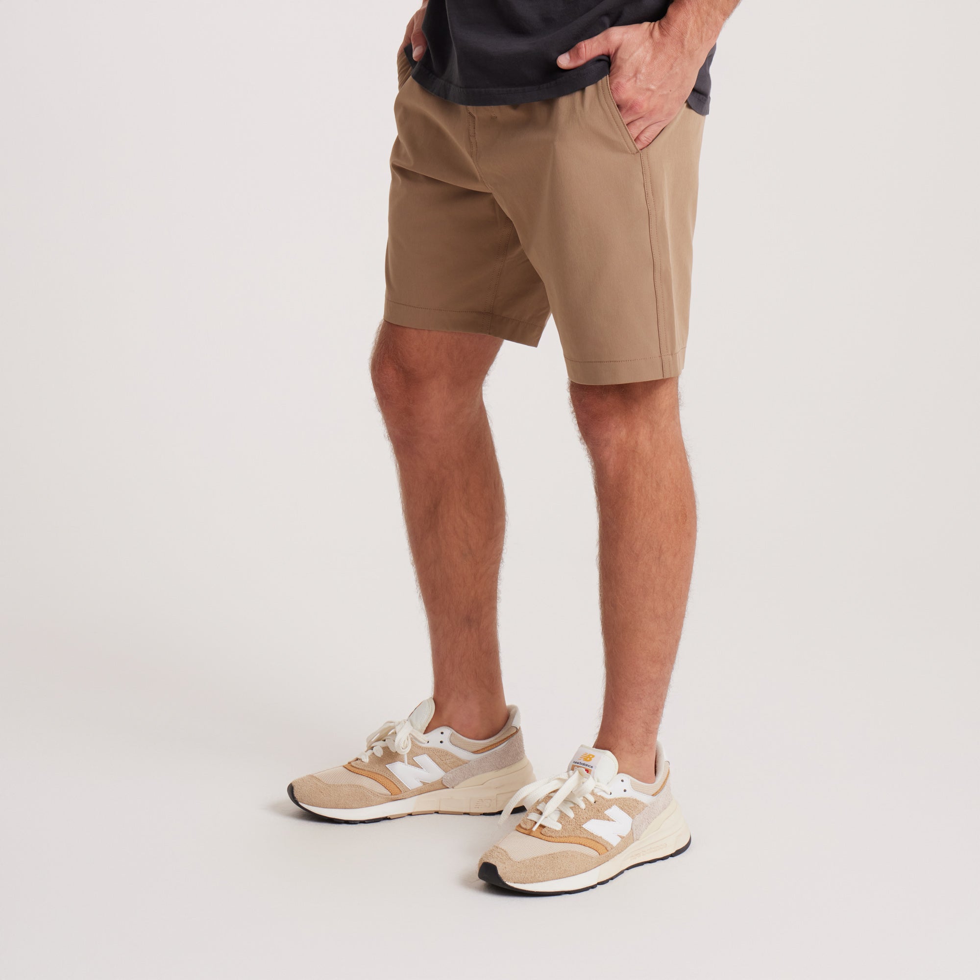 on-model Side angle of men's tan hybrid shorts, highlighting the flexible fabric and versatile style, ideal for both active and leisure activities.