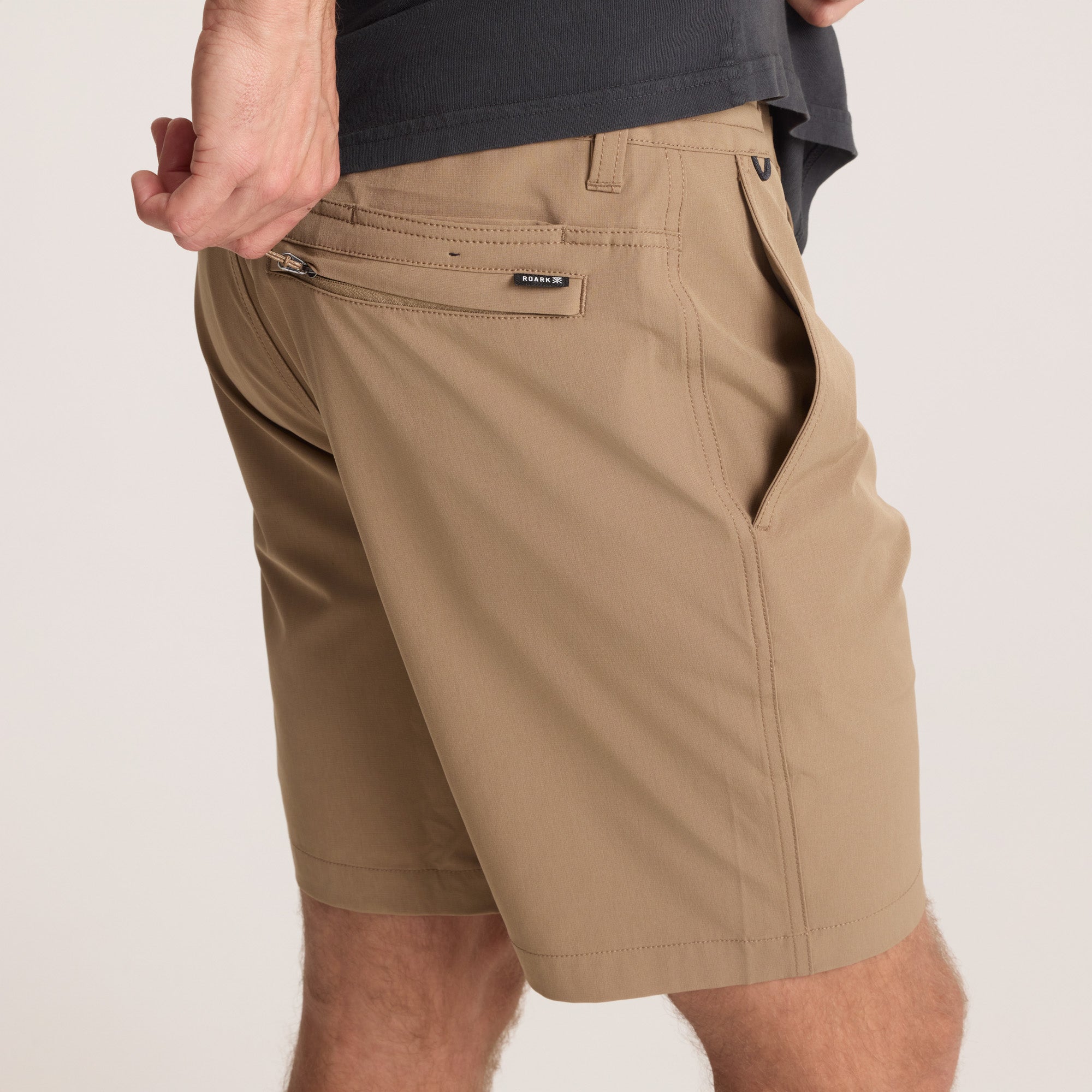 on-model Close-up of the back pocket of tan hybrid shorts with a zip closure, emphasizing secure storage for small essentials.