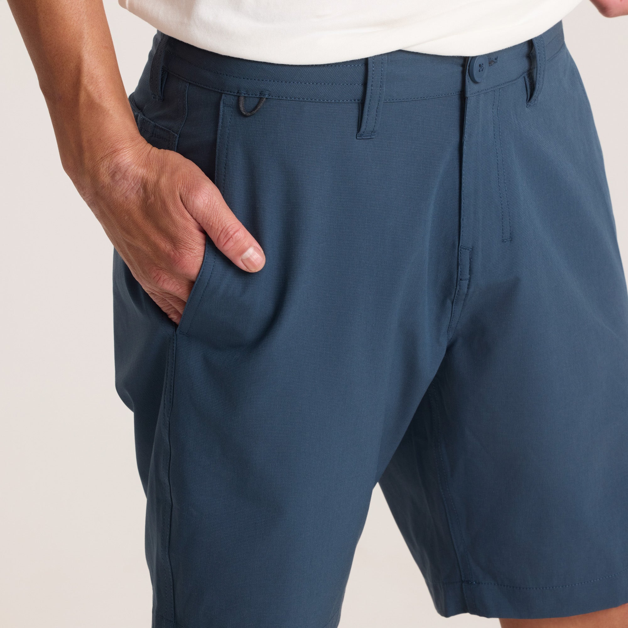 Close-up of navy hybrid shorts’ waistband and button detail, emphasizing precision stitching and quality craftsmanship.