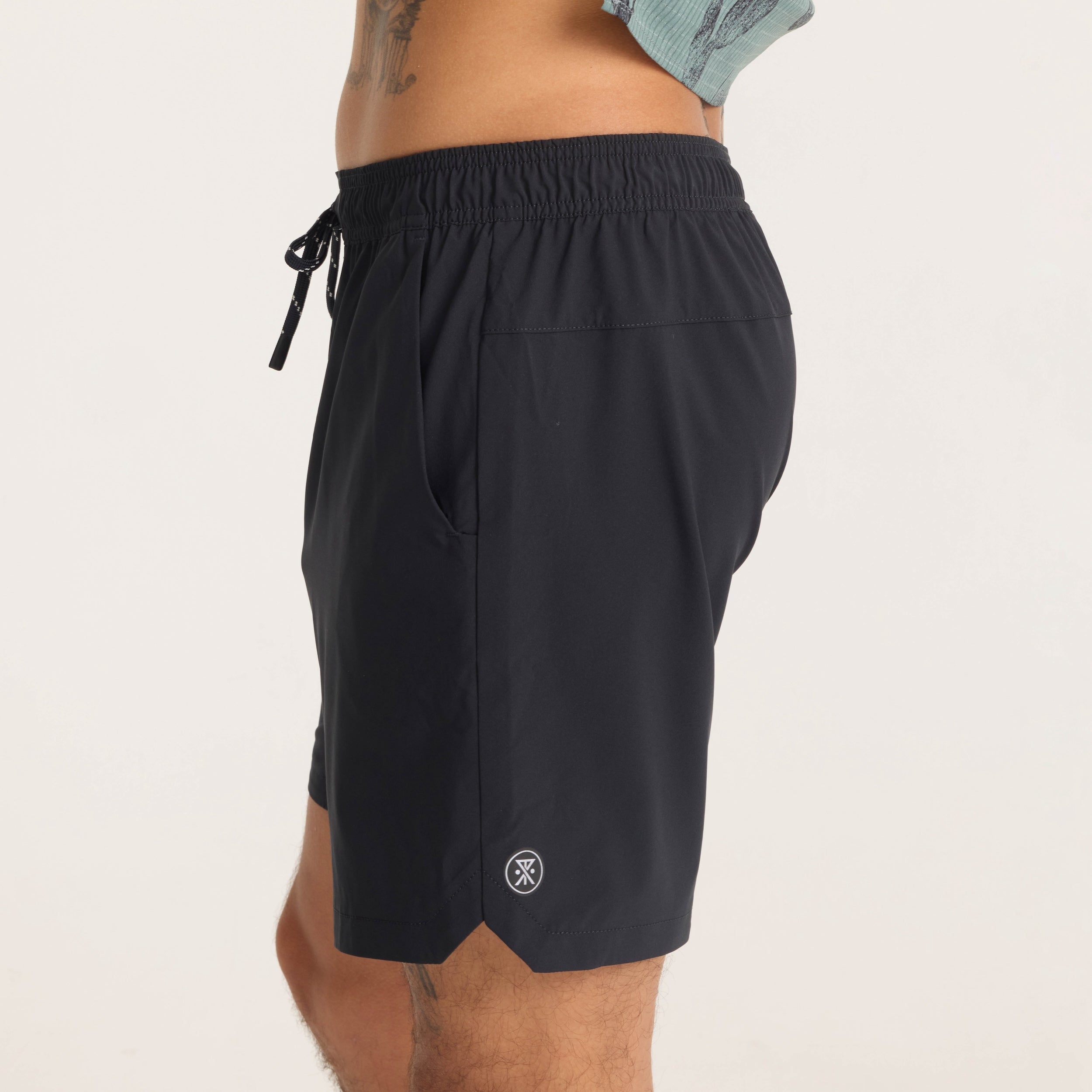 Close-up side view of black Serrano athletic shorts worn by model, featuring the Roark logo and water-resistant fabric finish.