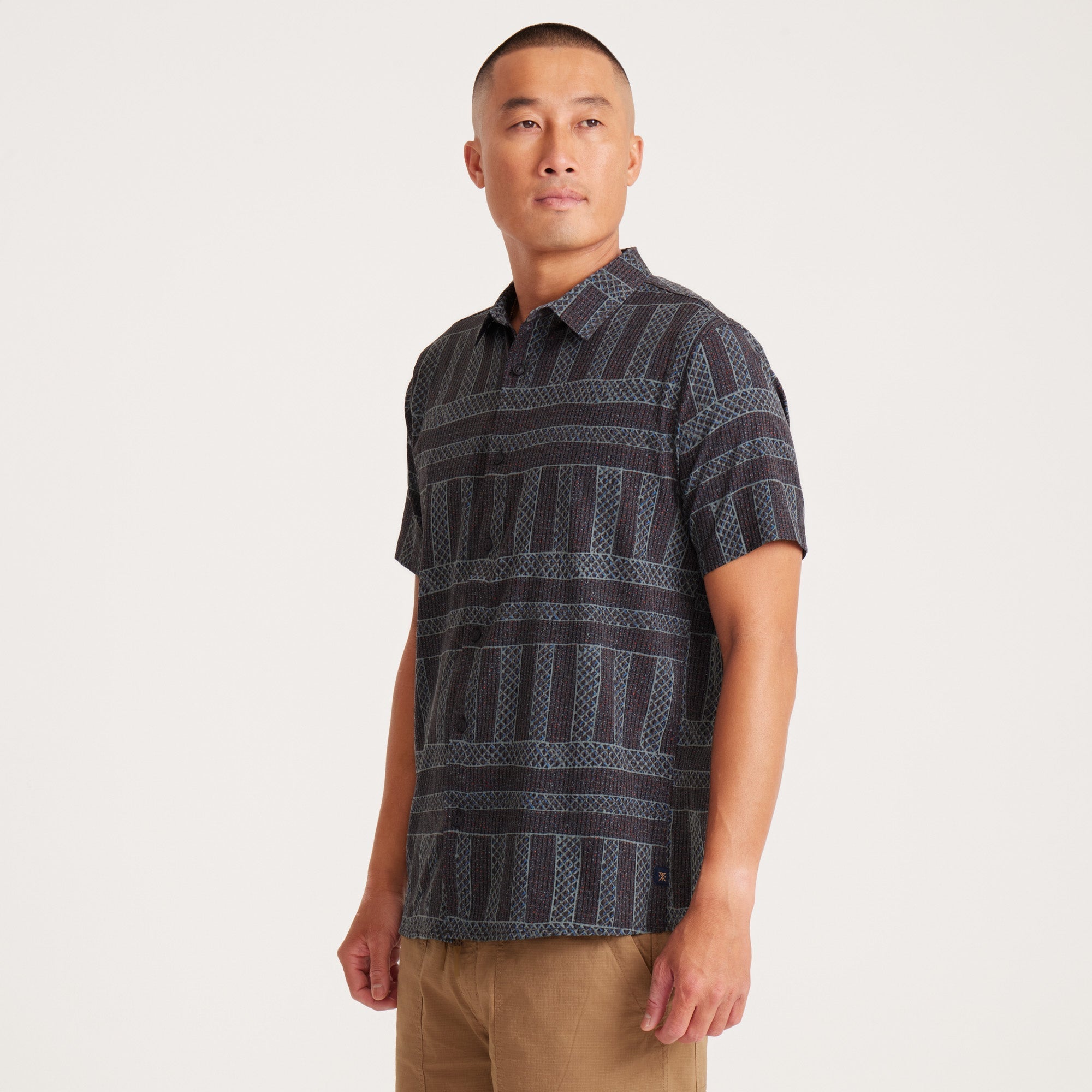 Model wearing a geometric-patterned short-sleeve button-up shirt, highlighting fit and casual design.