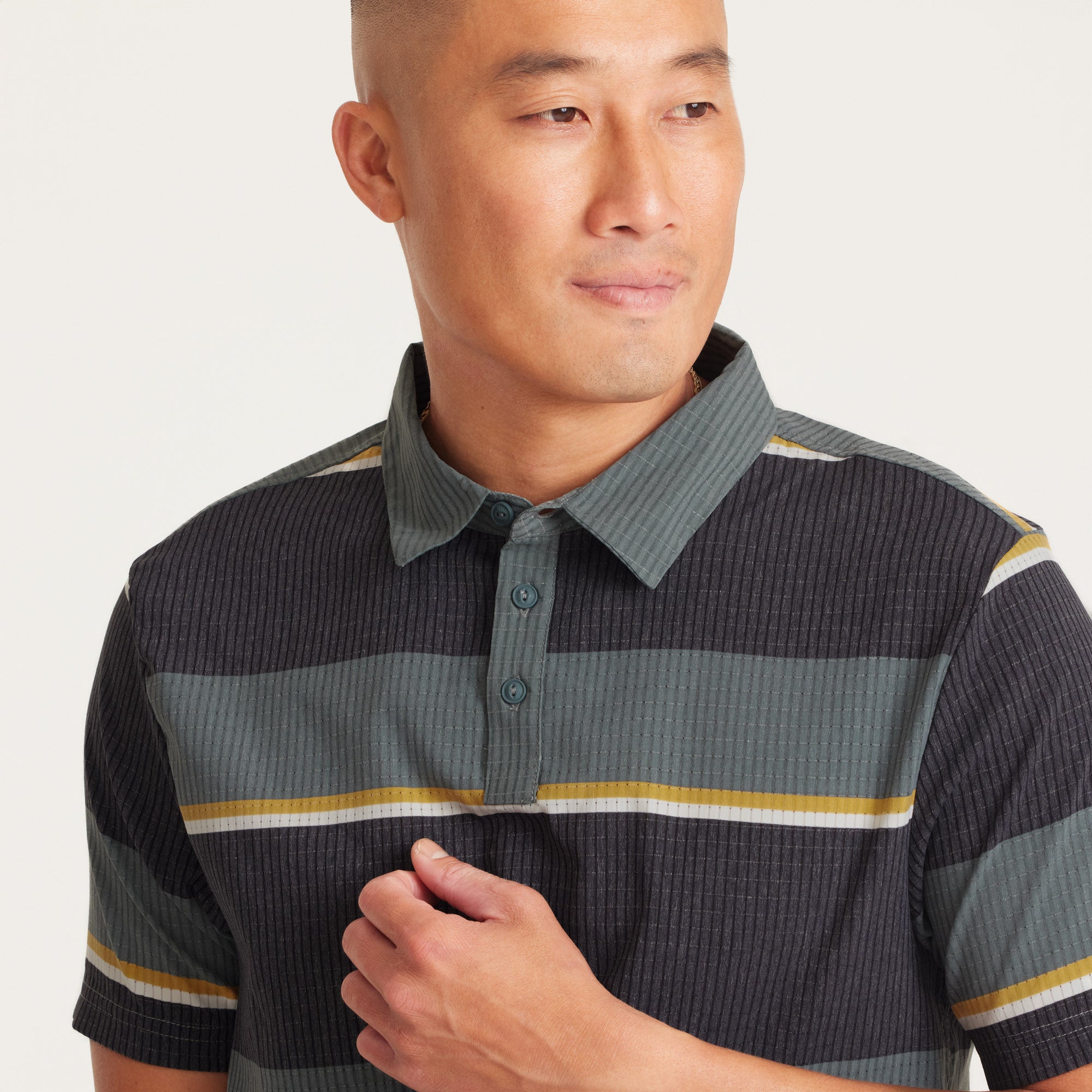 Close-up of the collar and button detail on a green and black striped performance polo shirt, featuring premium fabric and stylish accents.
