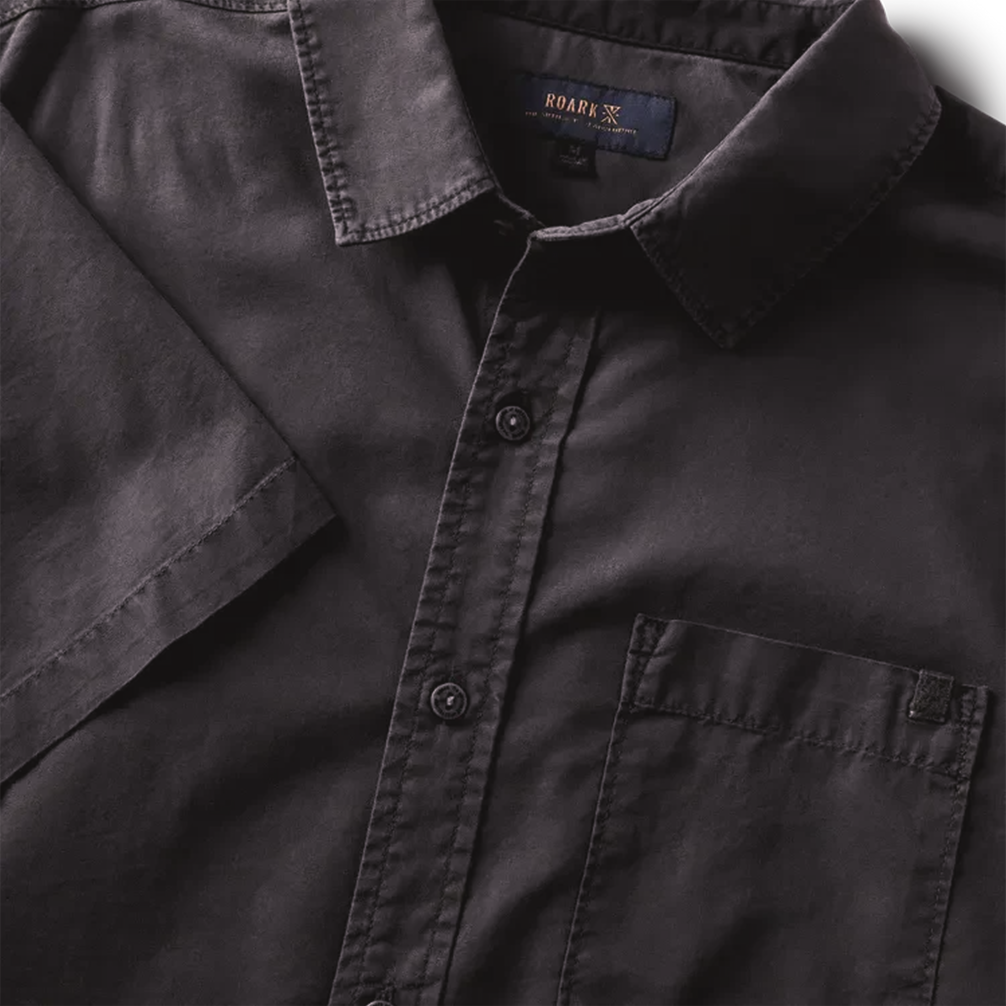 Close-up of black button-up shirt details, highlighting the buttons, collar, and front pocket for a refined look.
