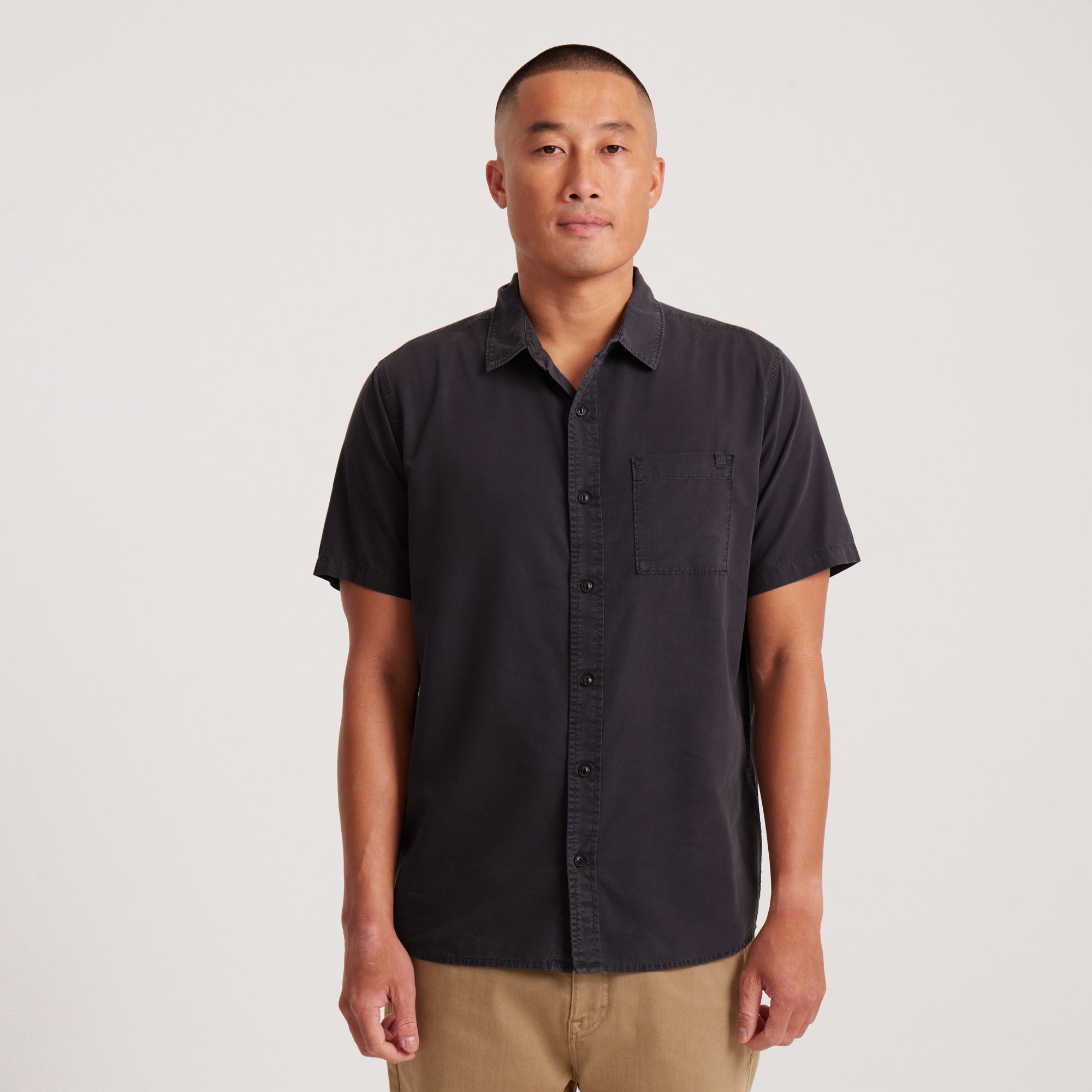 Front view of a black short-sleeve button-up shirt with a classic collar and chest pocket, perfect for casual wear.