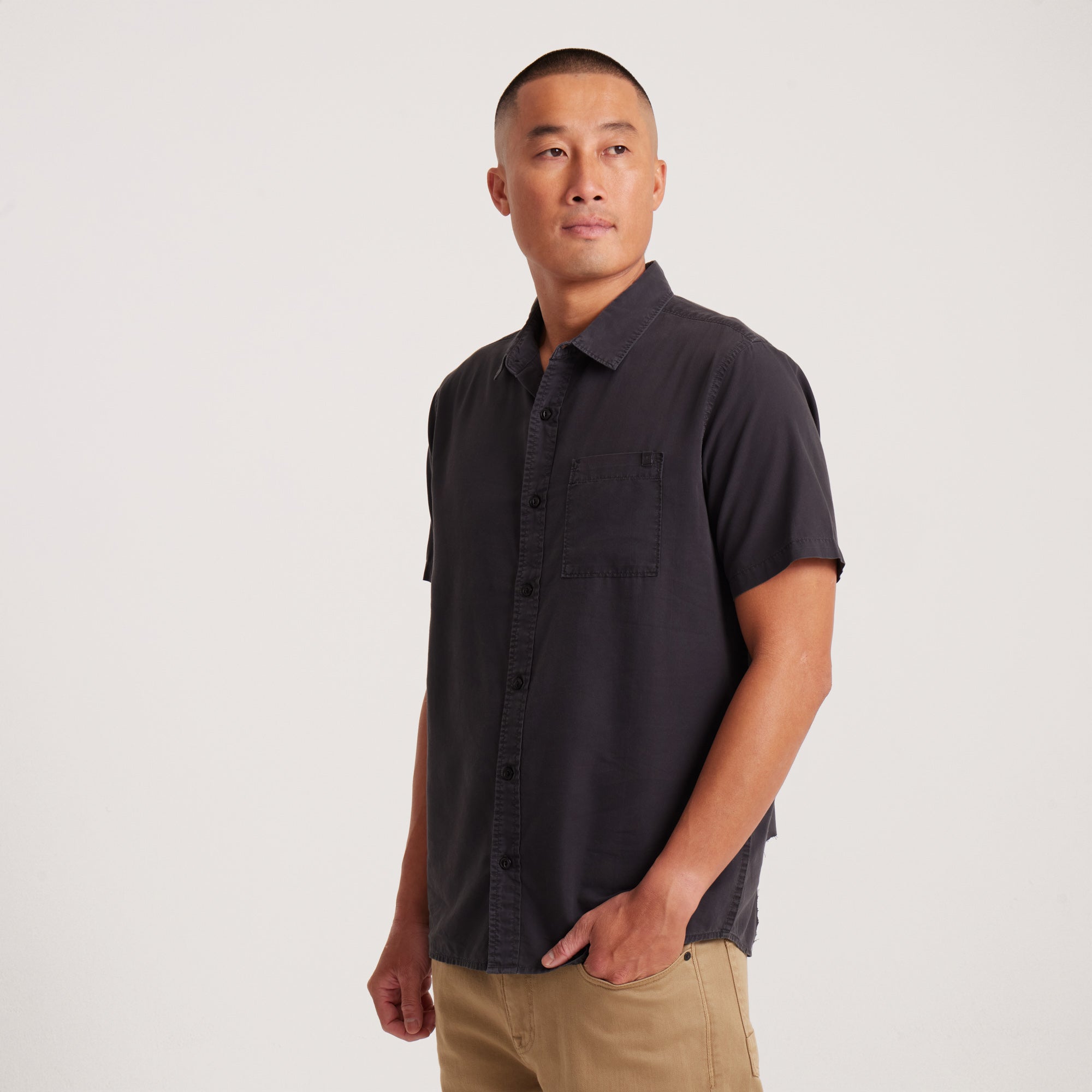 Side angle of a black short-sleeve button-up shirt with clean lines, showcasing a relaxed and modern fit.
