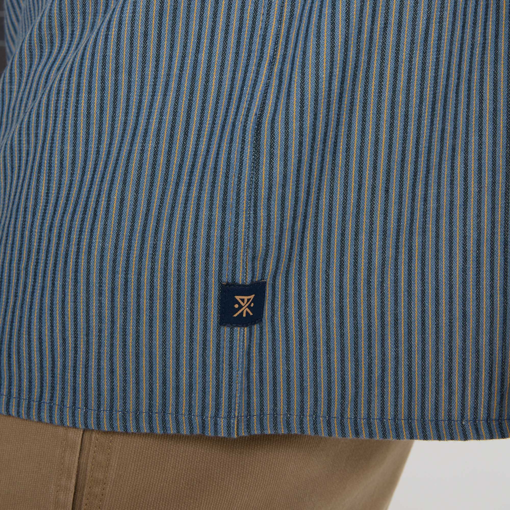 Detail of rugged denim dress shirt featuring durable buttons, designed for adventure and travel, by Roark