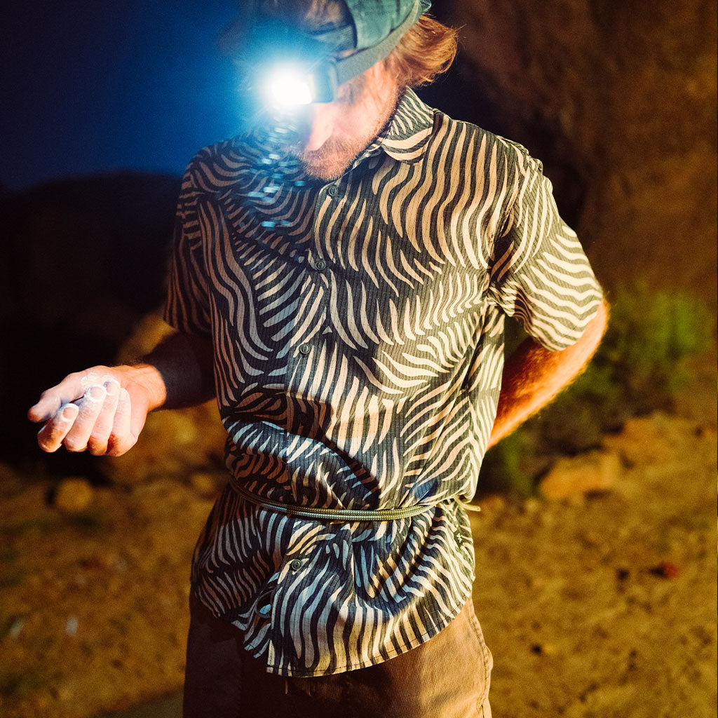 Person wearing a zebra-patterned shirt with a flashlight on a dark background