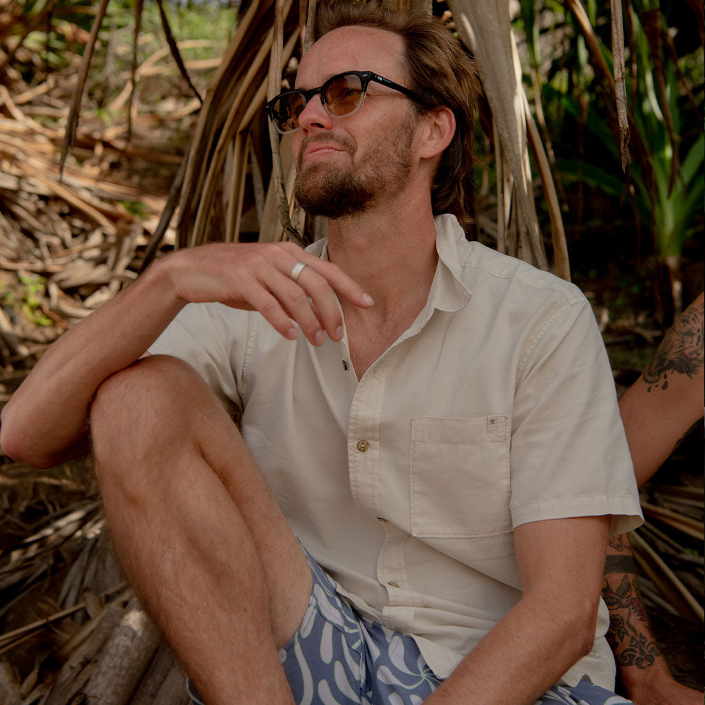 Man sitting outdoors wearing sunglasses and a light shirt