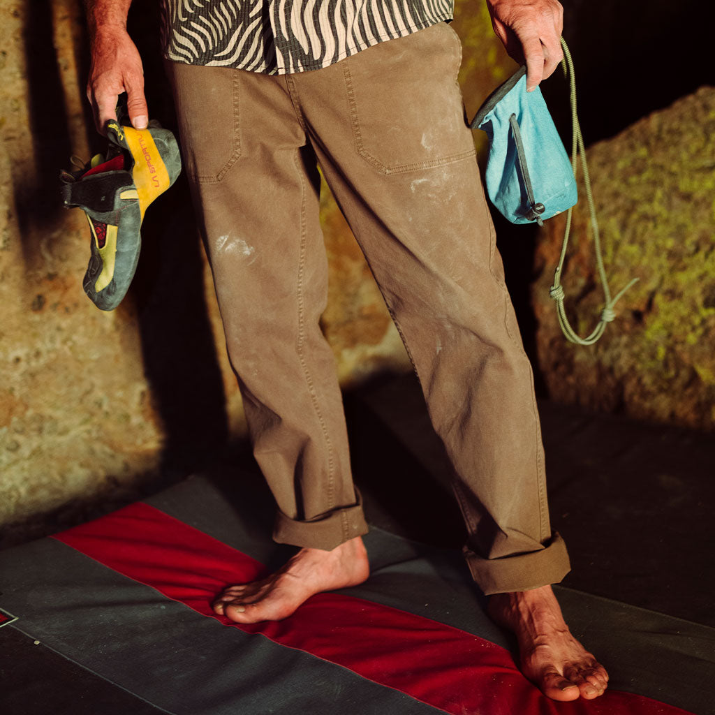 Person wearing brown pants with climbing equipment on a red and black mat.