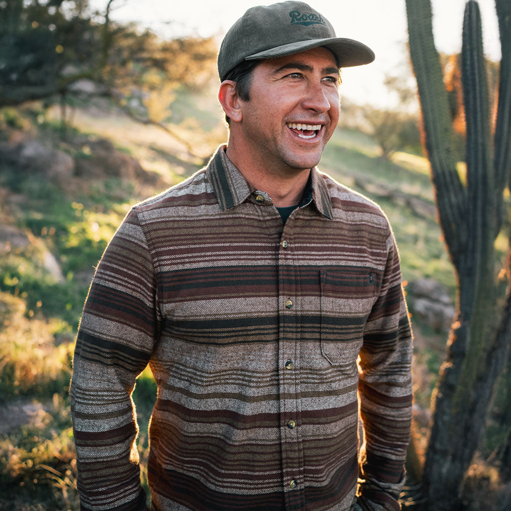 Guy in a brown stripe Roark flannel shirt with cactus in the background