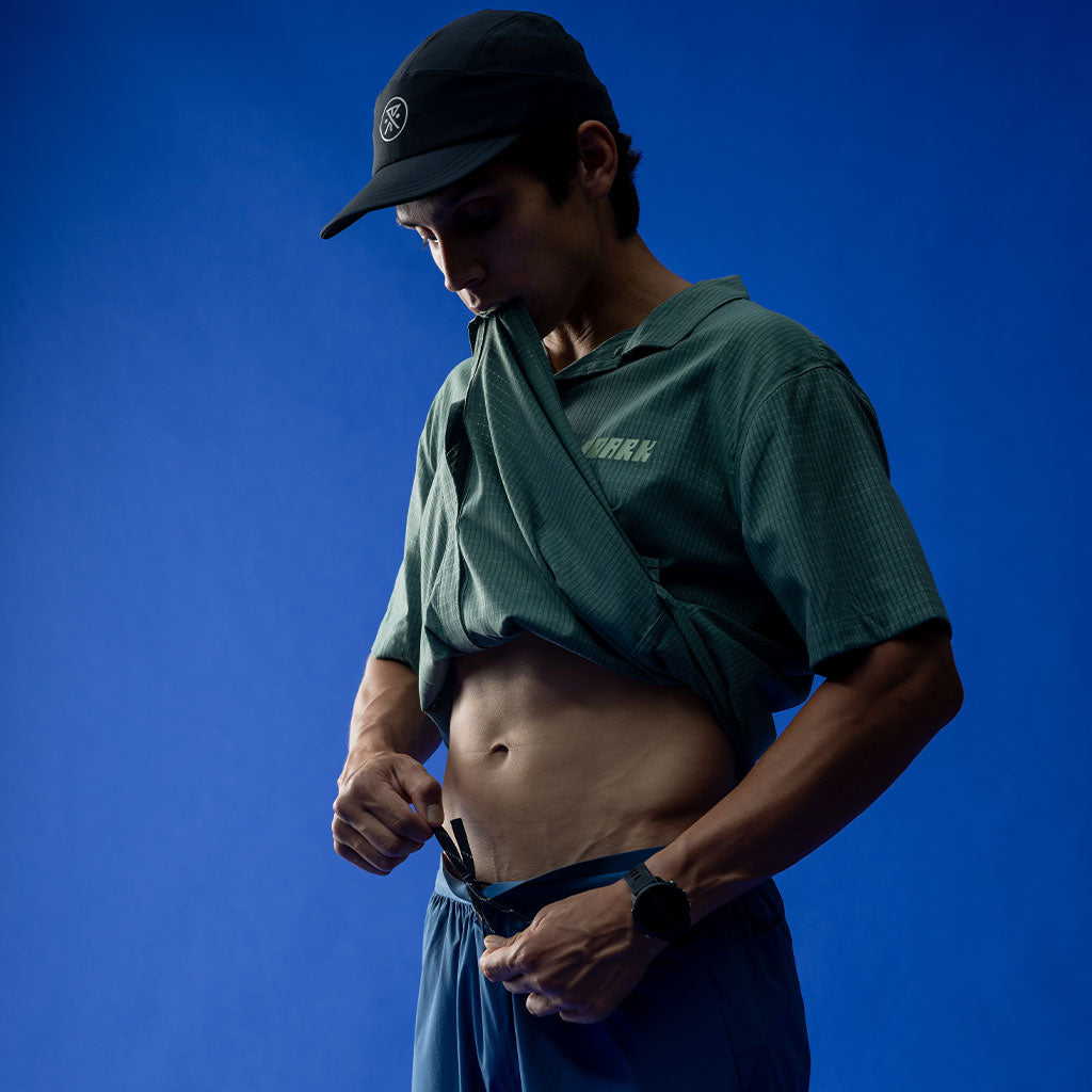 Man wearing a green shirt and blue shorts against a blue background