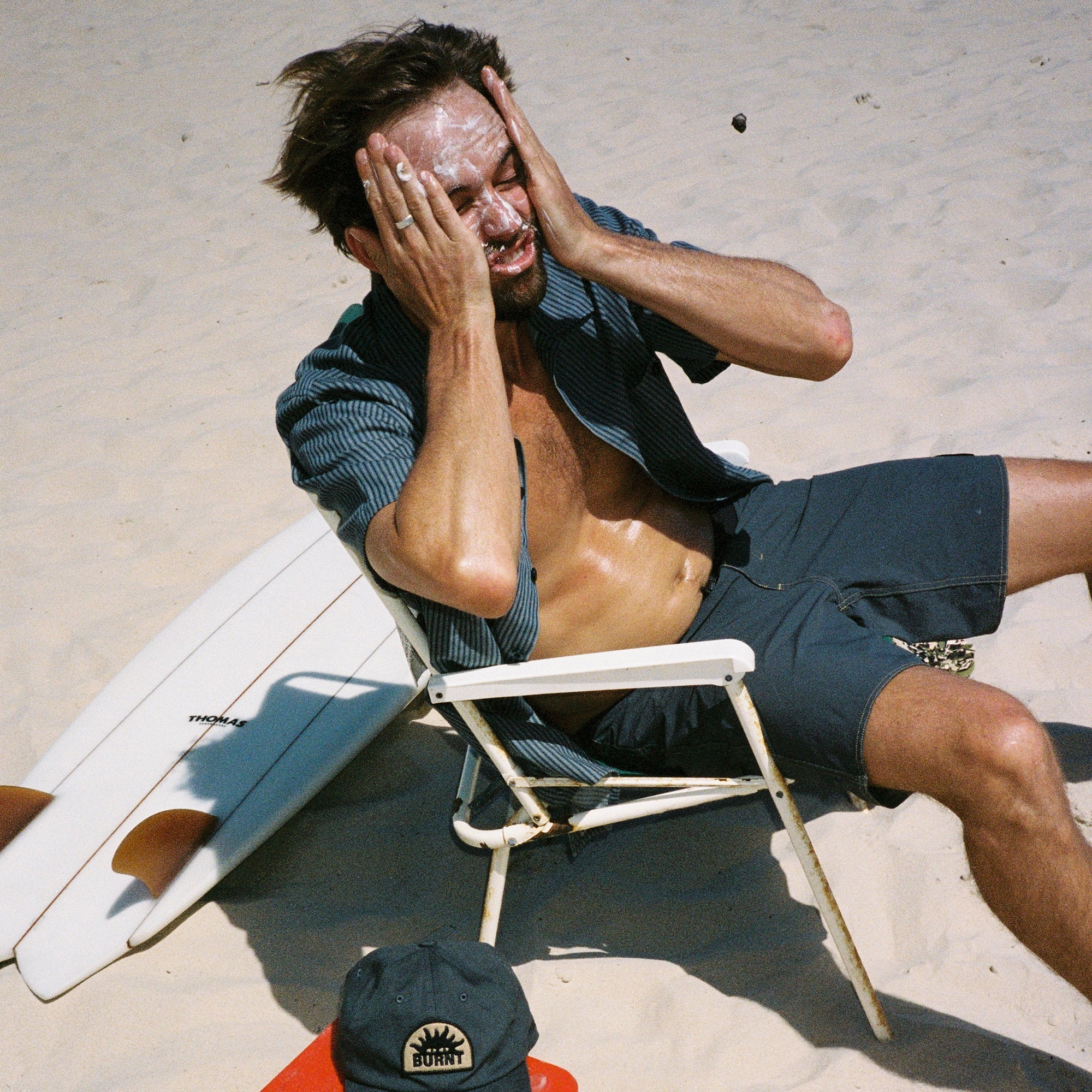 sun smart man on the beach applying sunscreen just like mama used to do it