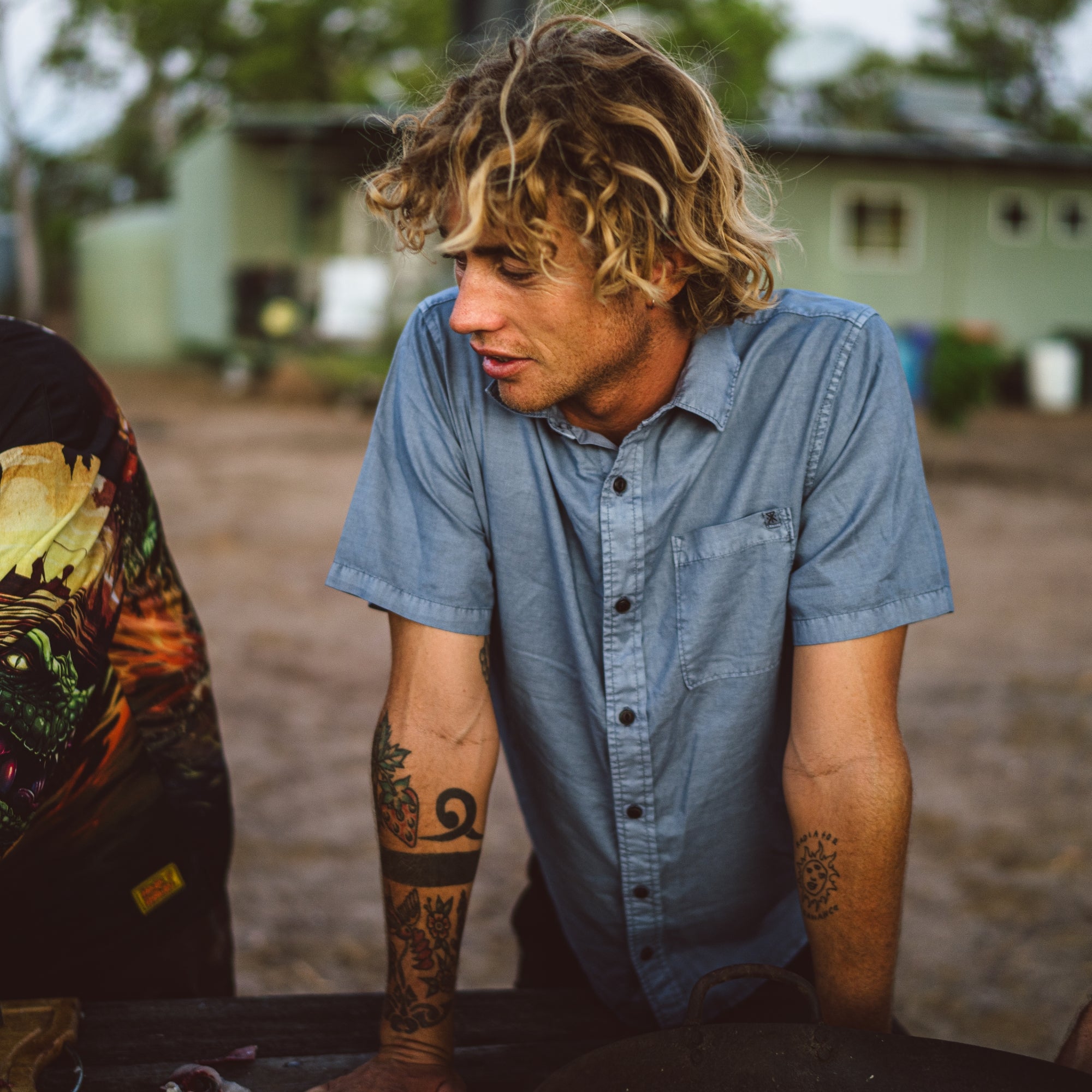 Man with tattoos wearing a blue shirt outdoors