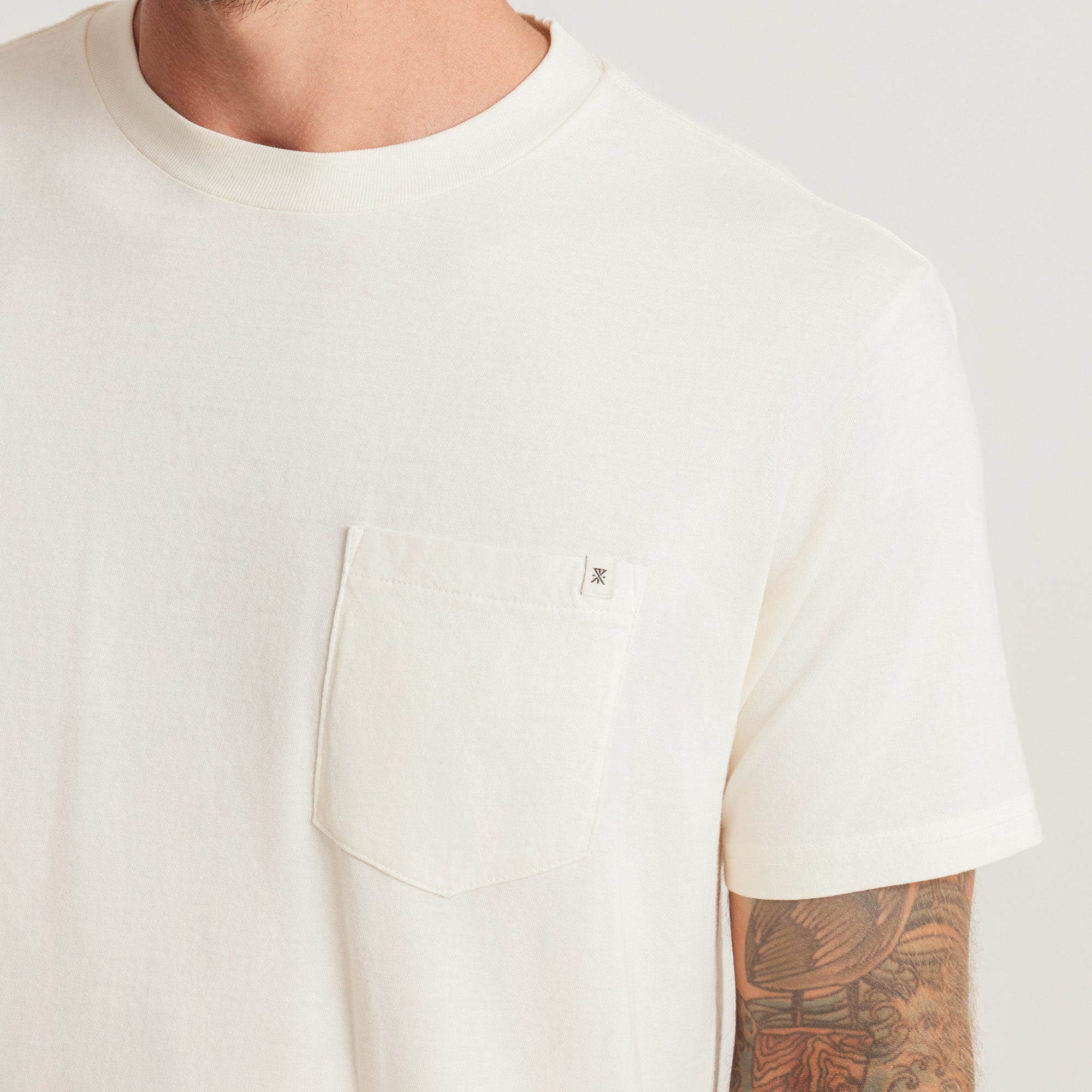 A close-up of the white Roark t-shirt, emphasizing the stylish pocket detail and subtle branding for a modern touch.