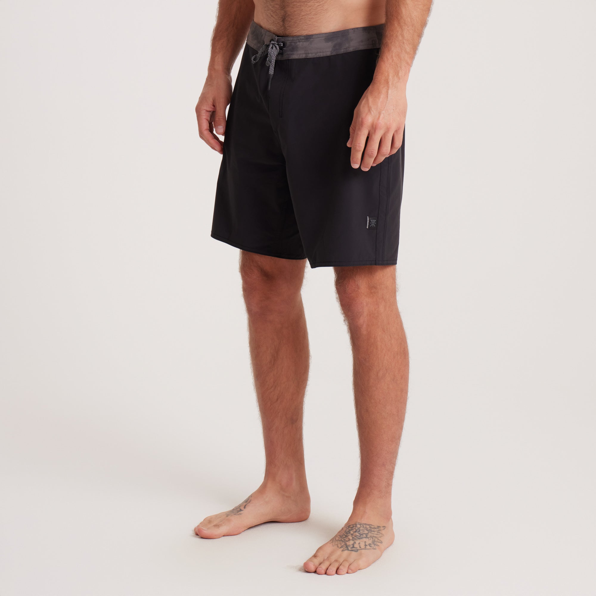 Side view of Roark black boardshorts highlighting sleek design and functional details, perfect for outdoor adventures.
