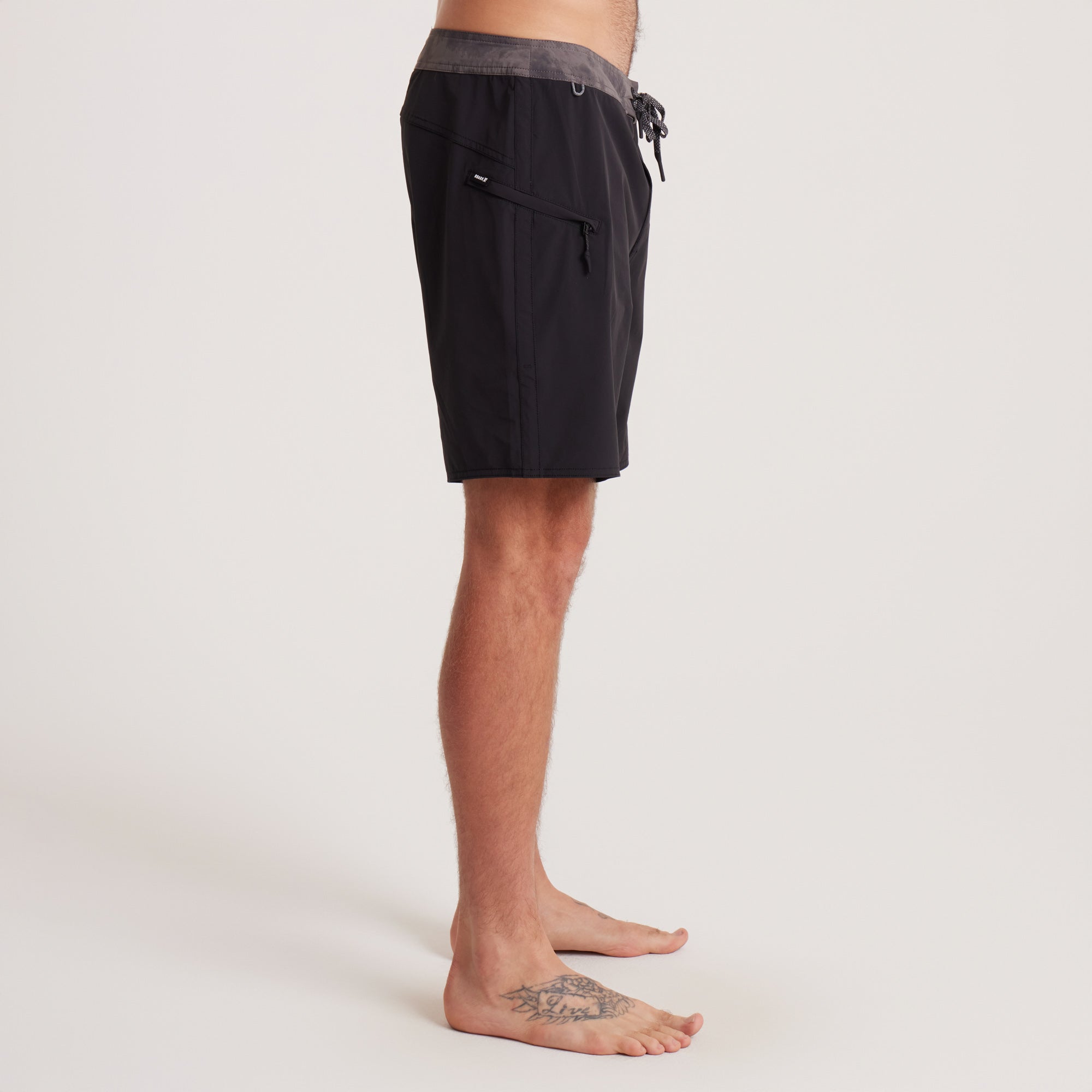 Side profile of Roark black boardshorts with a close-up of the waistband and premium construction, ideal for active lifestyles.