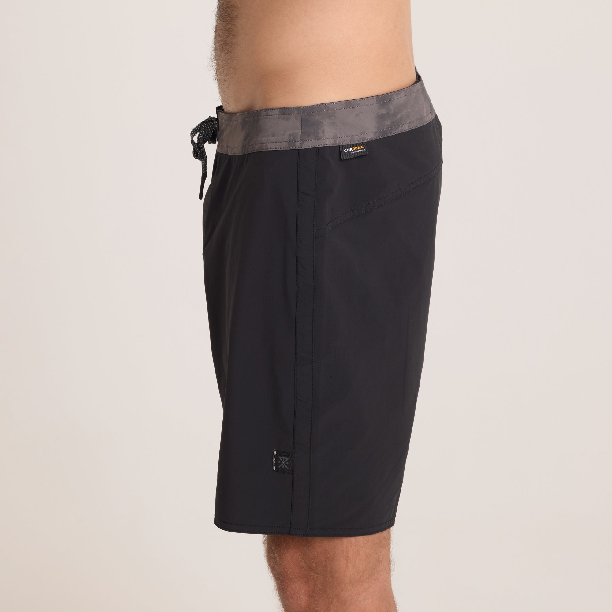 Detailed side view of Roark black boardshorts, blending a minimalistic design with high-performance fabric for water and outdoor activities.