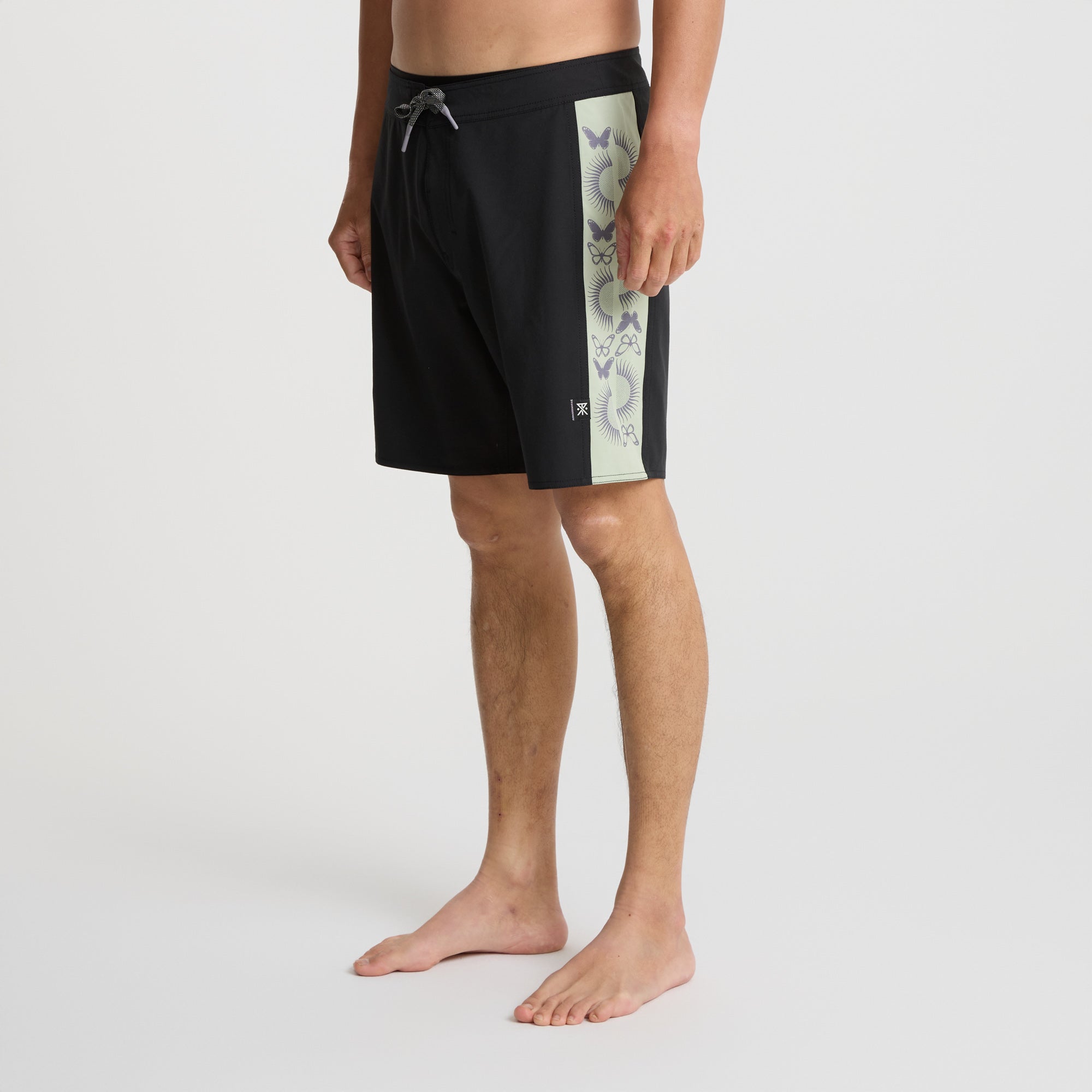 Versatile black Roark boardshorts displayed against a rugged outcrop, ideal for adventure and outdoor activities.