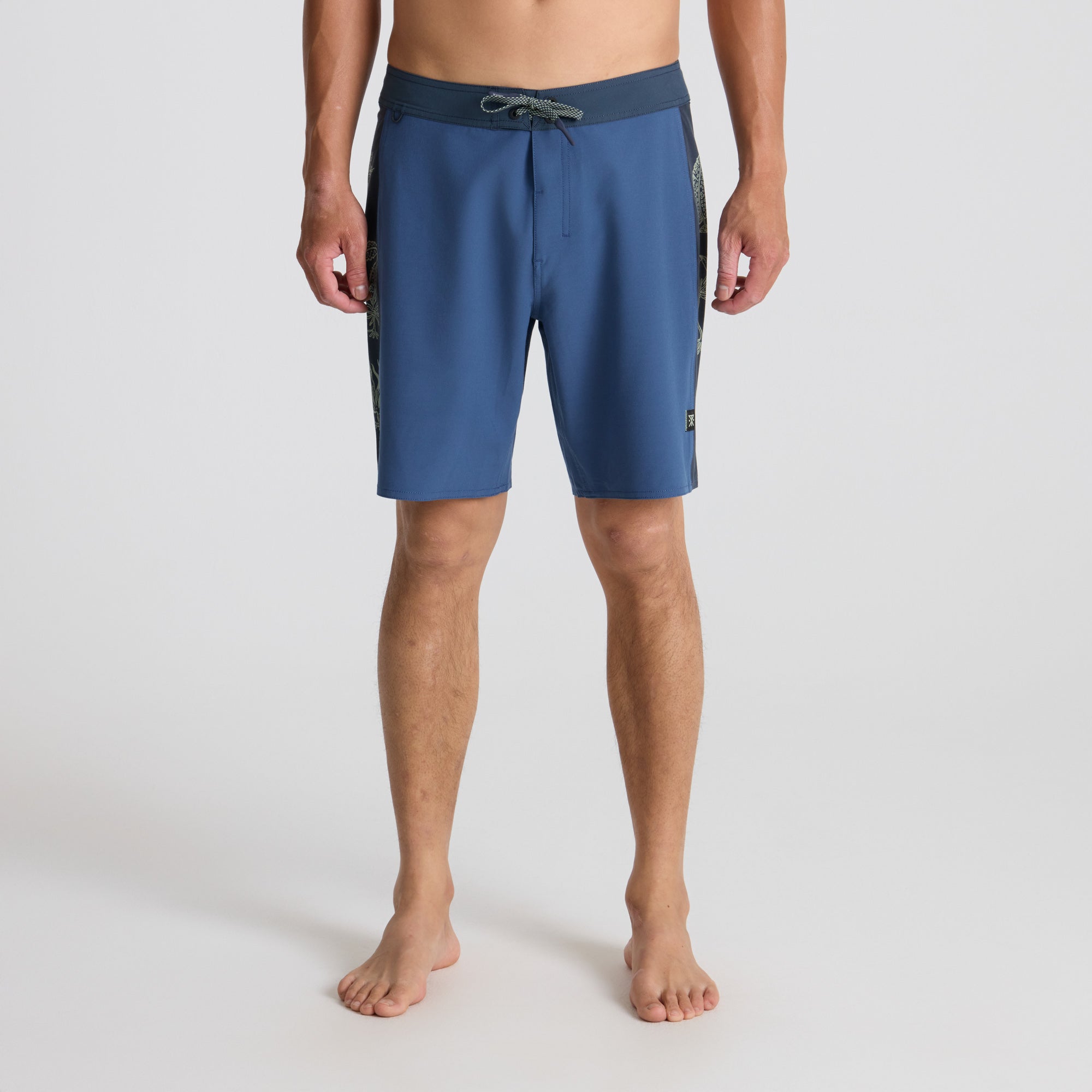 Man in tropical bay wearing Roark boardshorts, embodying a spirit of adventure and the outdoors.