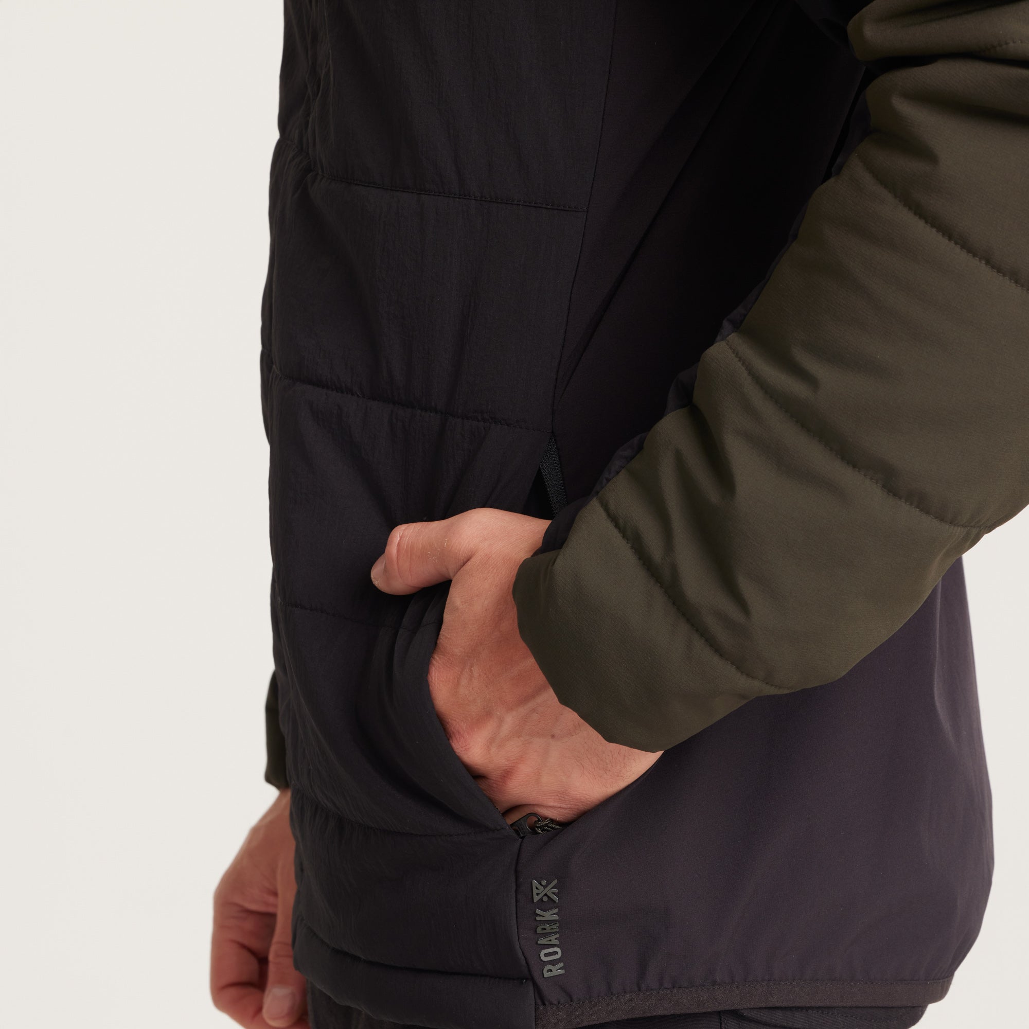 Man wearing a green and black hooded jacket with the hood up, offering full protection against the elements.