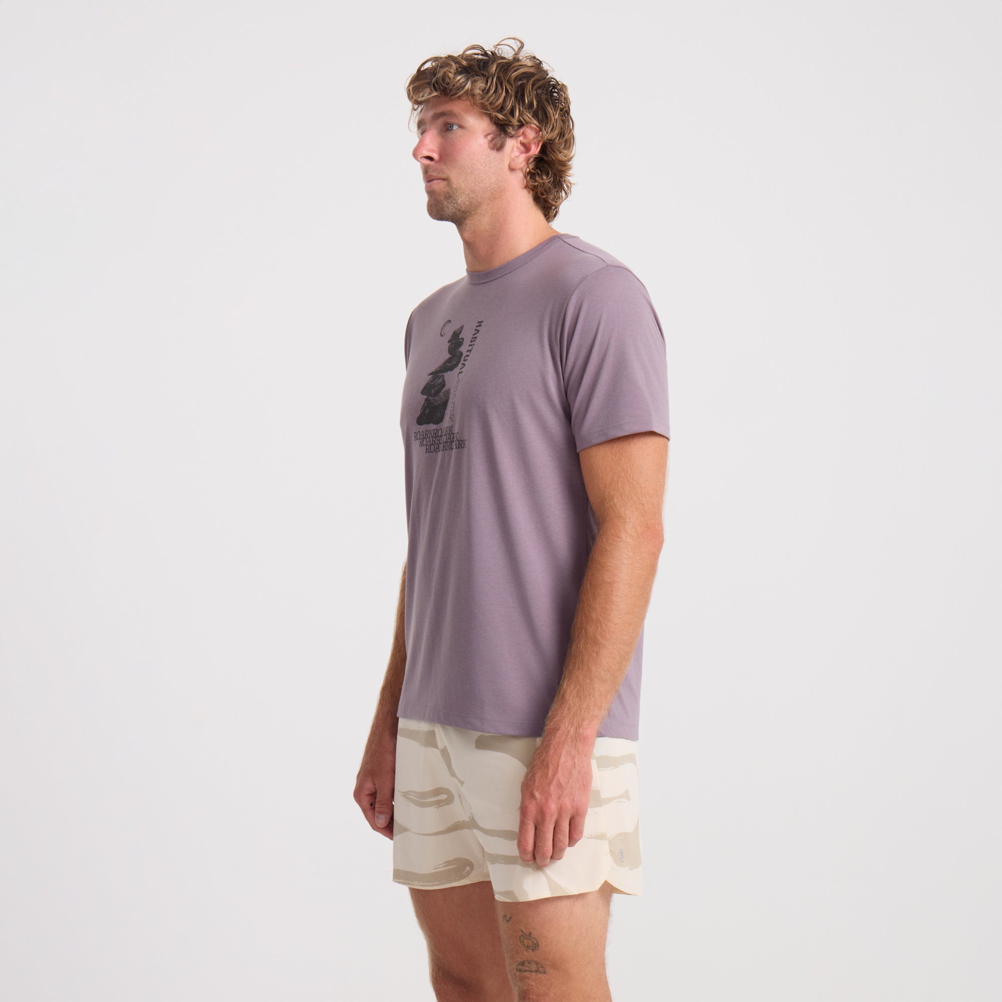 Model wearing Roark active outdoor apparel, featuring an active shirt paired with boardshorts, ideal for adventure and travel.