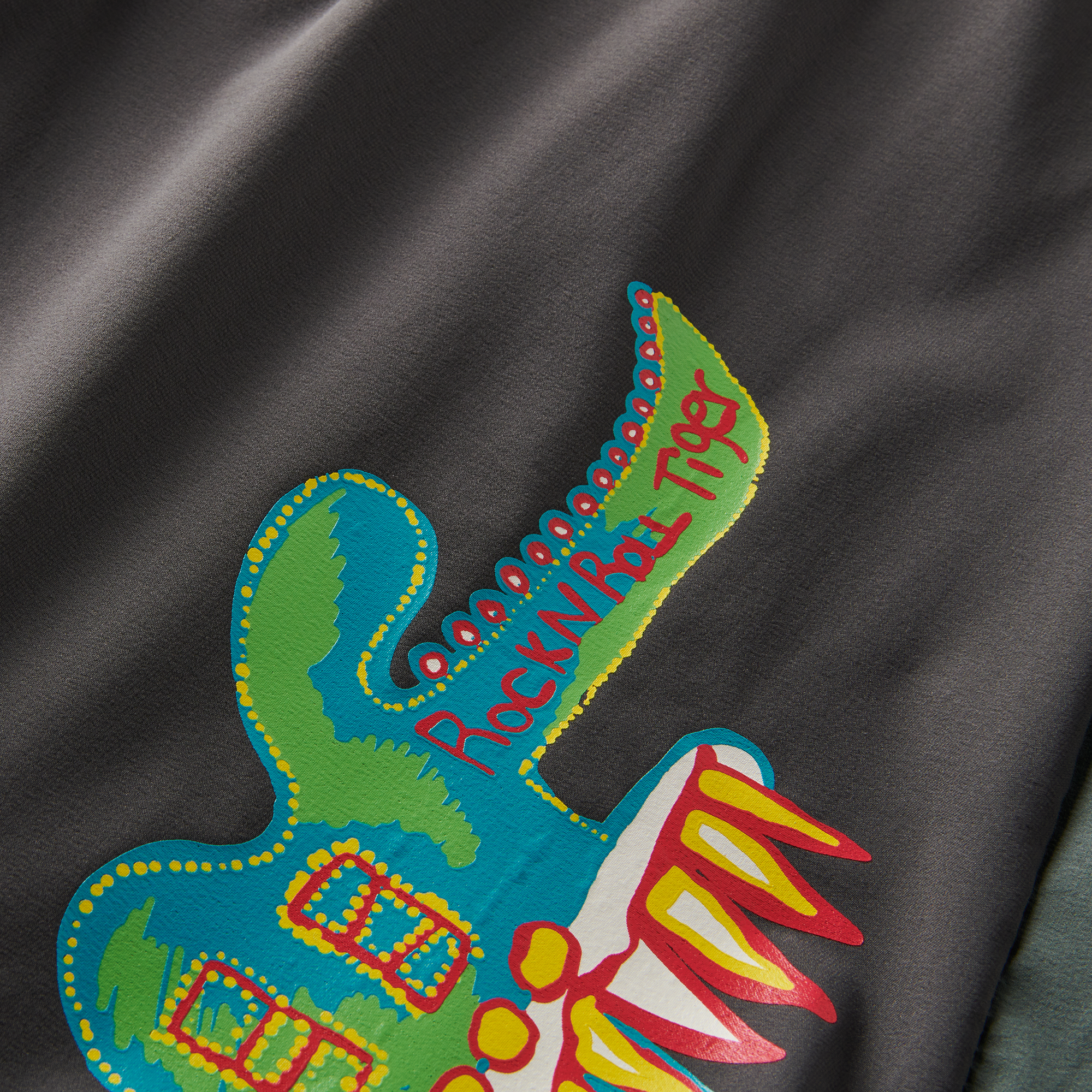 Close-up of vibrant 'Rock N Roll Tour' graphic print on shorts, showcasing unique artistic design and bold colors.
