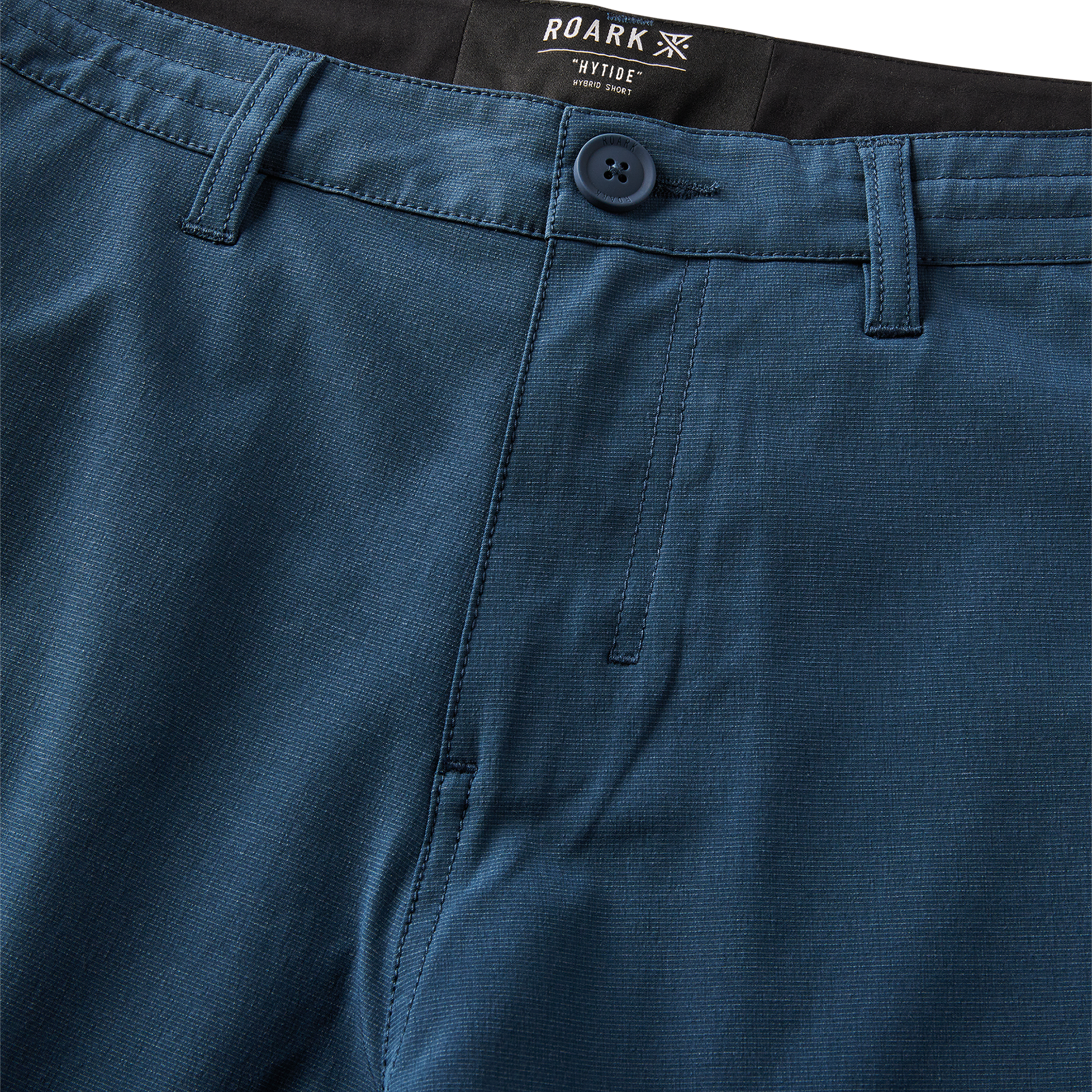 Man wearing a navy Roark adventure jacket while exploring a rugged coastal landscape