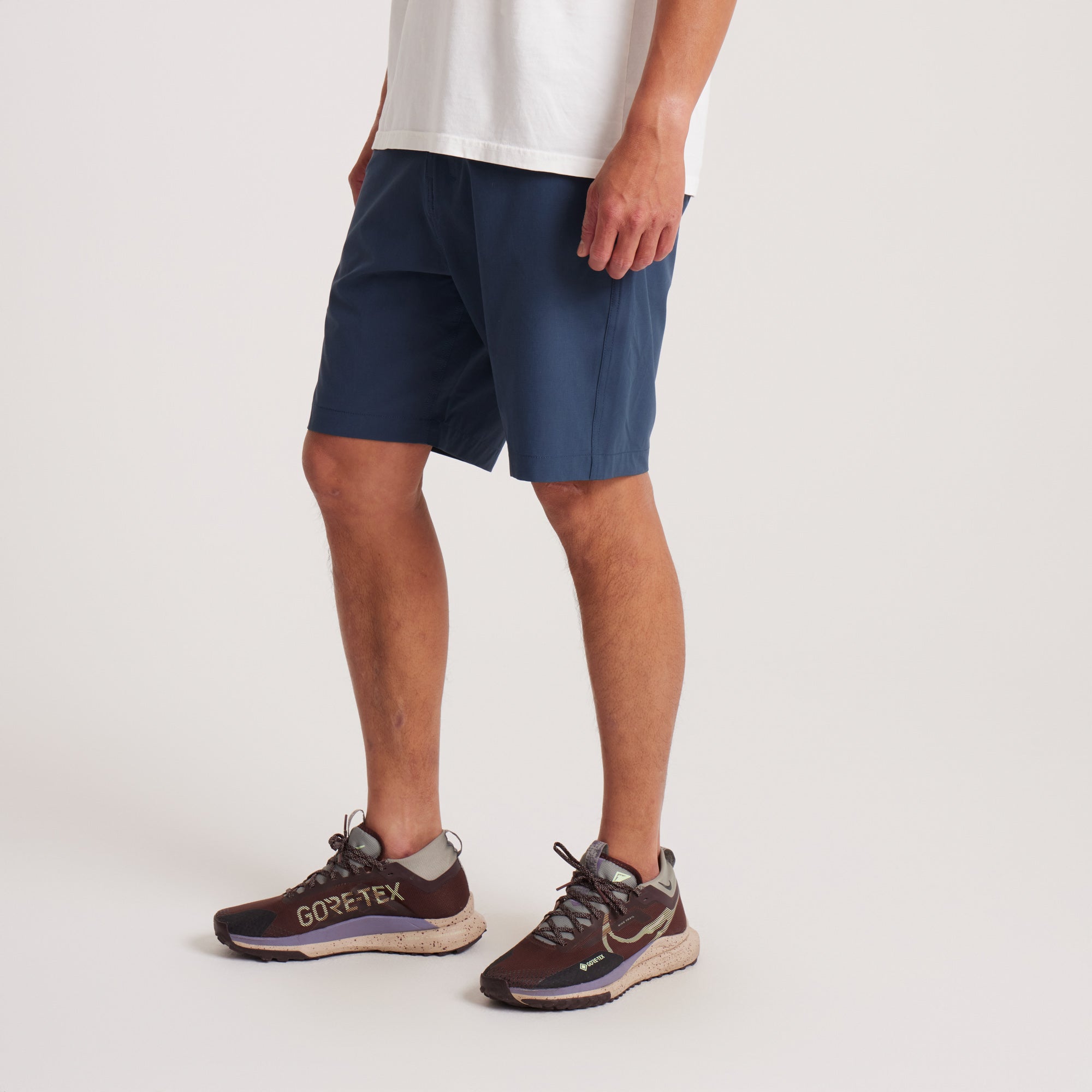 Side view of navy hybrid shorts on a model, displaying their tailored fit and functional pocket design.