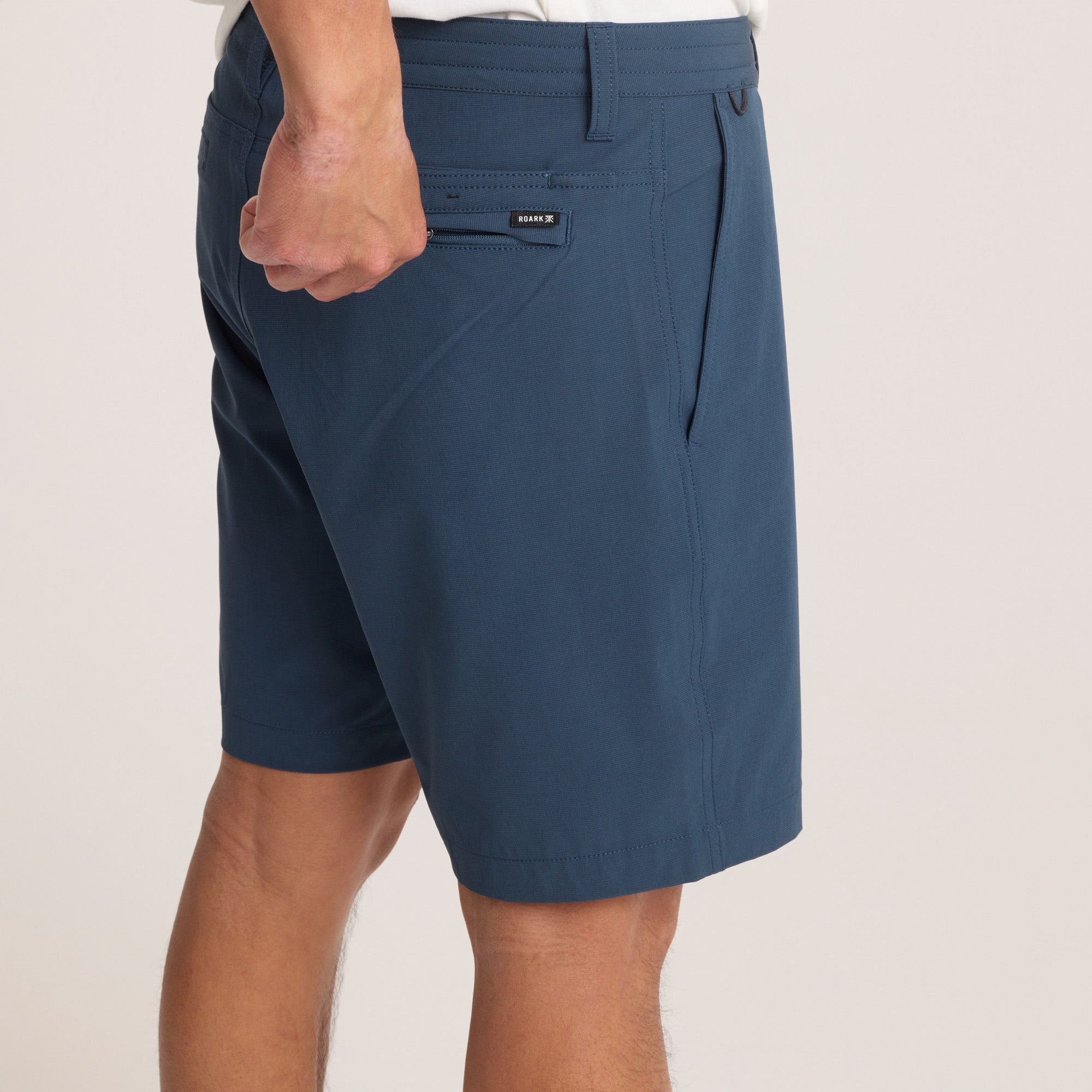 Back close-up of navy hybrid shorts highlighting the branded zip pocket, ensuring secure storage and added style.