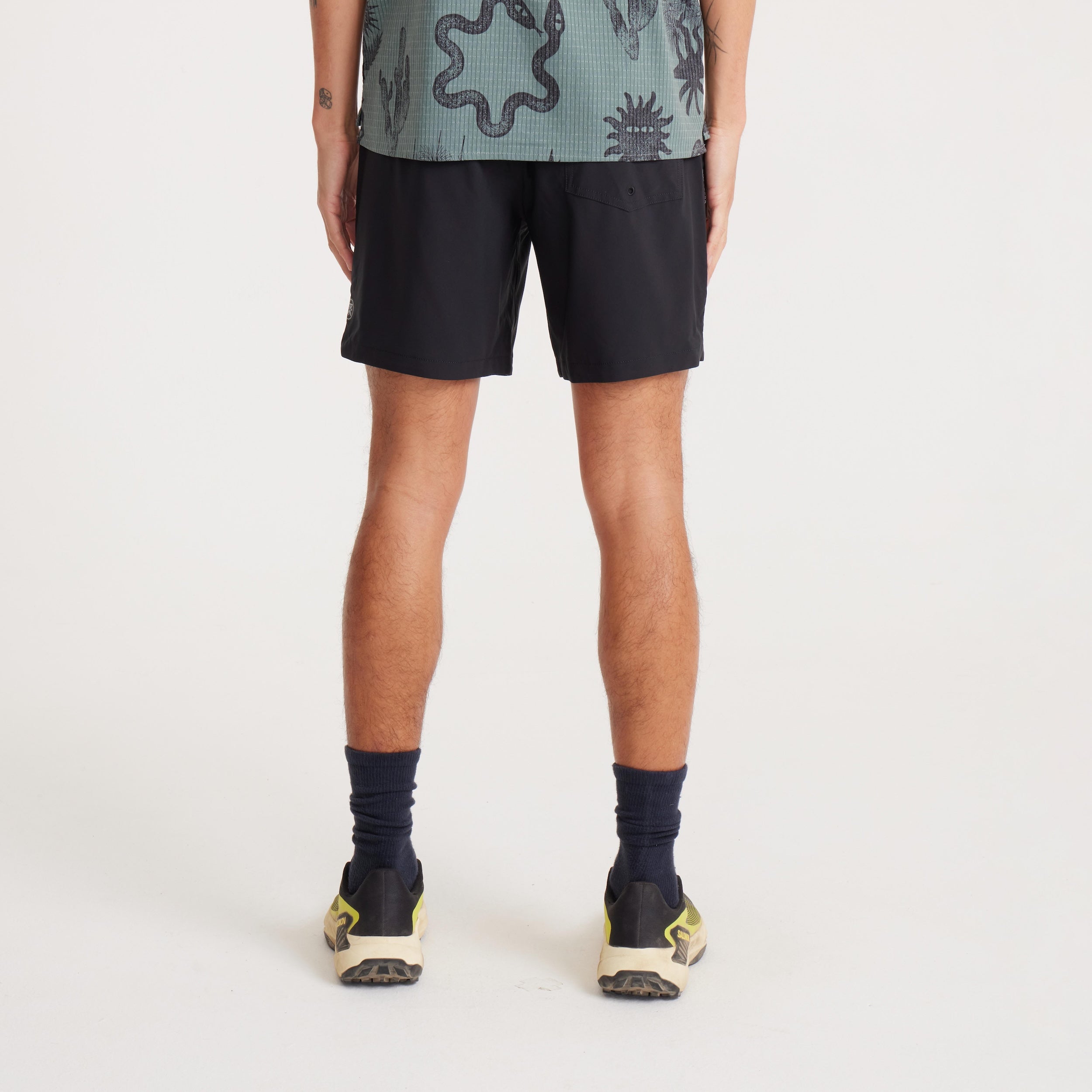 Back view of model wearing black Serrano shorts, showing the rear patch pocket with a secure YKK zipper for functionality and style.