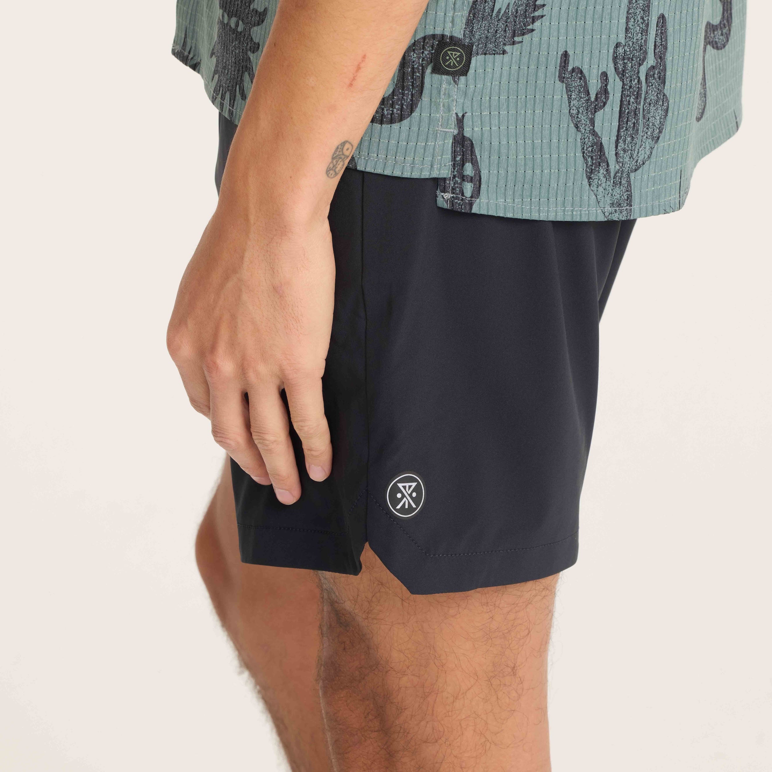 Detailed close-up of Roark logo on black Serrano shorts, representing premium design and outdoor-inspired functionality.