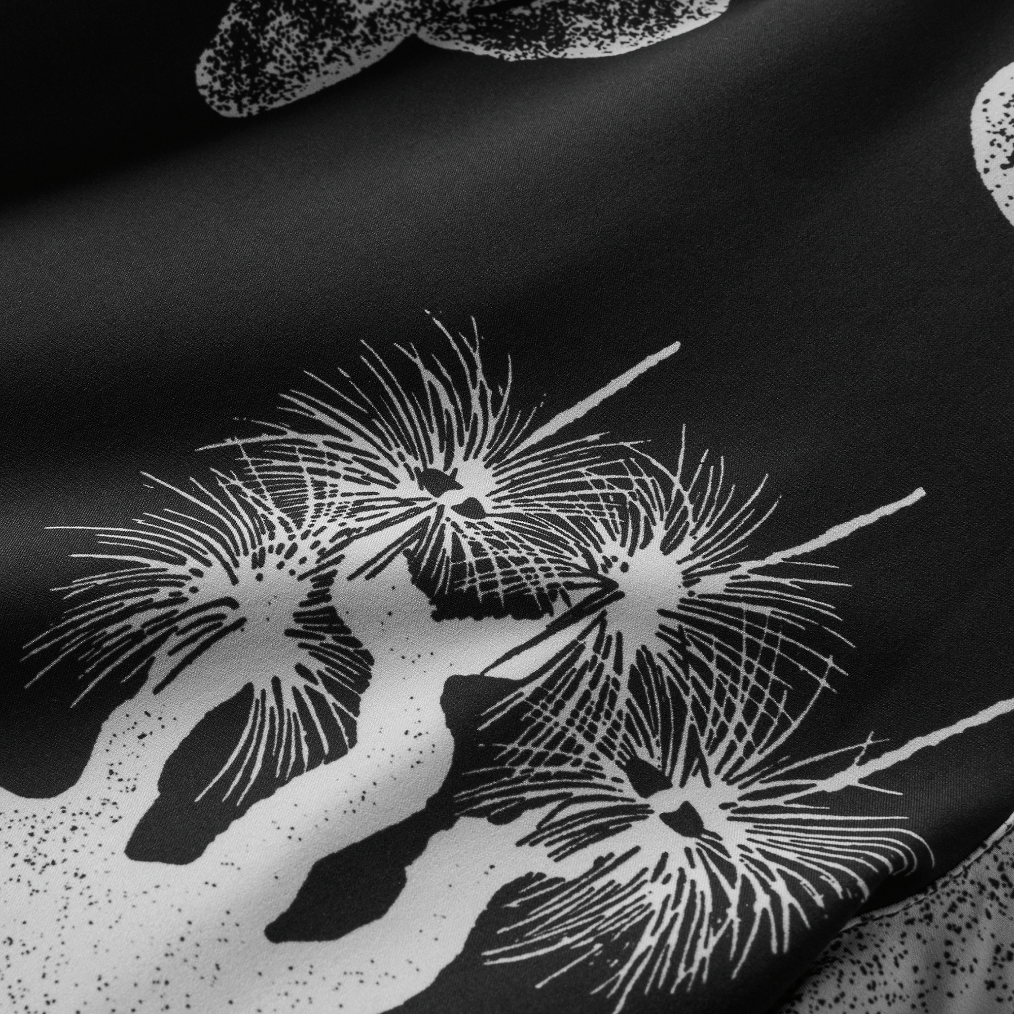 Close-up view of intricate white graphic prints on black fabric, featuring desert-inspired designs, perfect for showcasing a bold and stylish look.