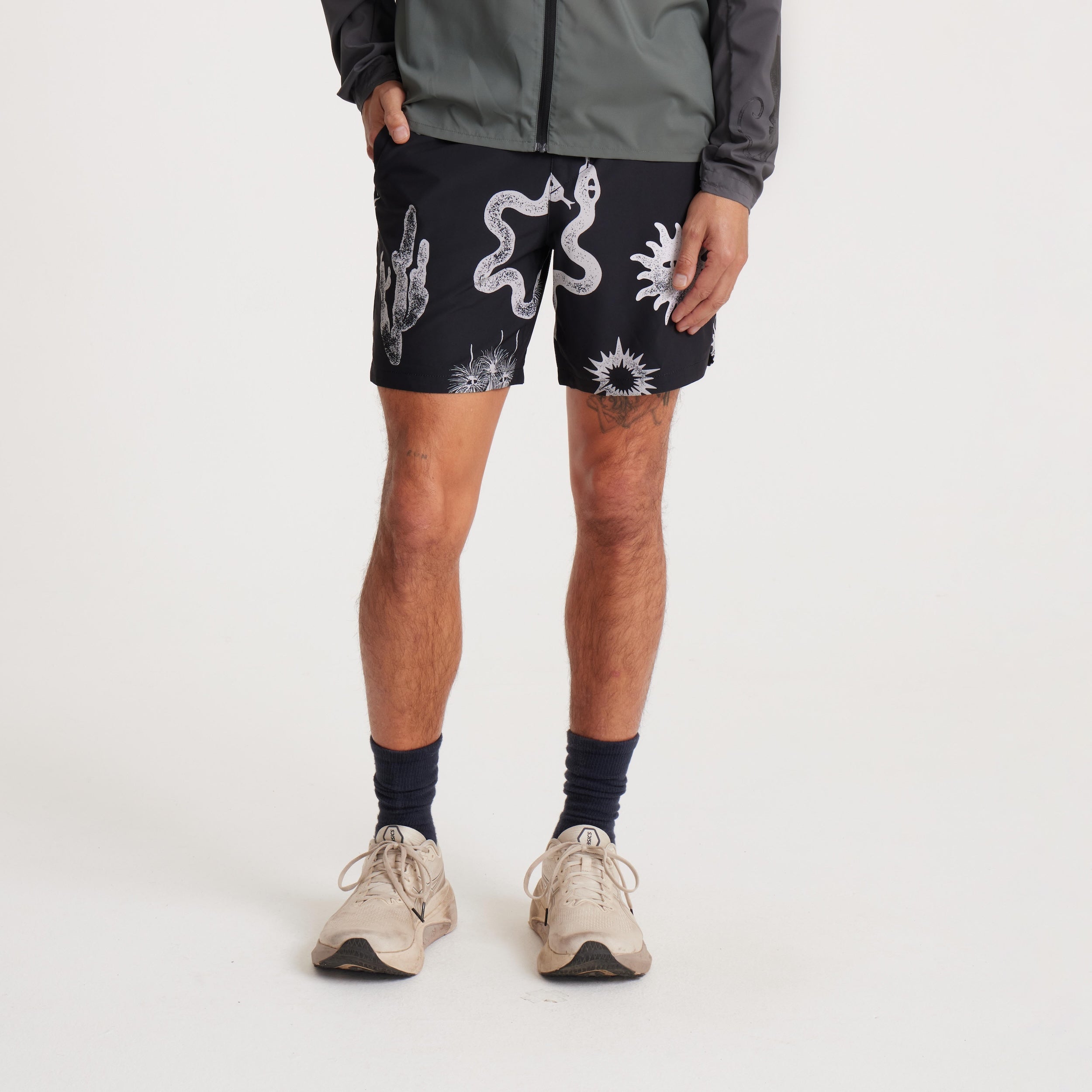 Front angled view of a model showcasing black swim shorts with bold white designs, including cacti and sun motifs, perfect for beach and outdoor adventures.