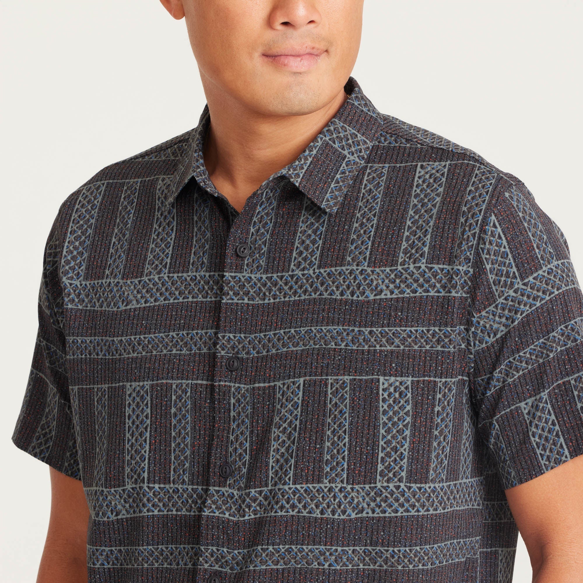 Model styled in a geometric-patterned shirt paired with light khaki pants, perfect for a casual outfit.
