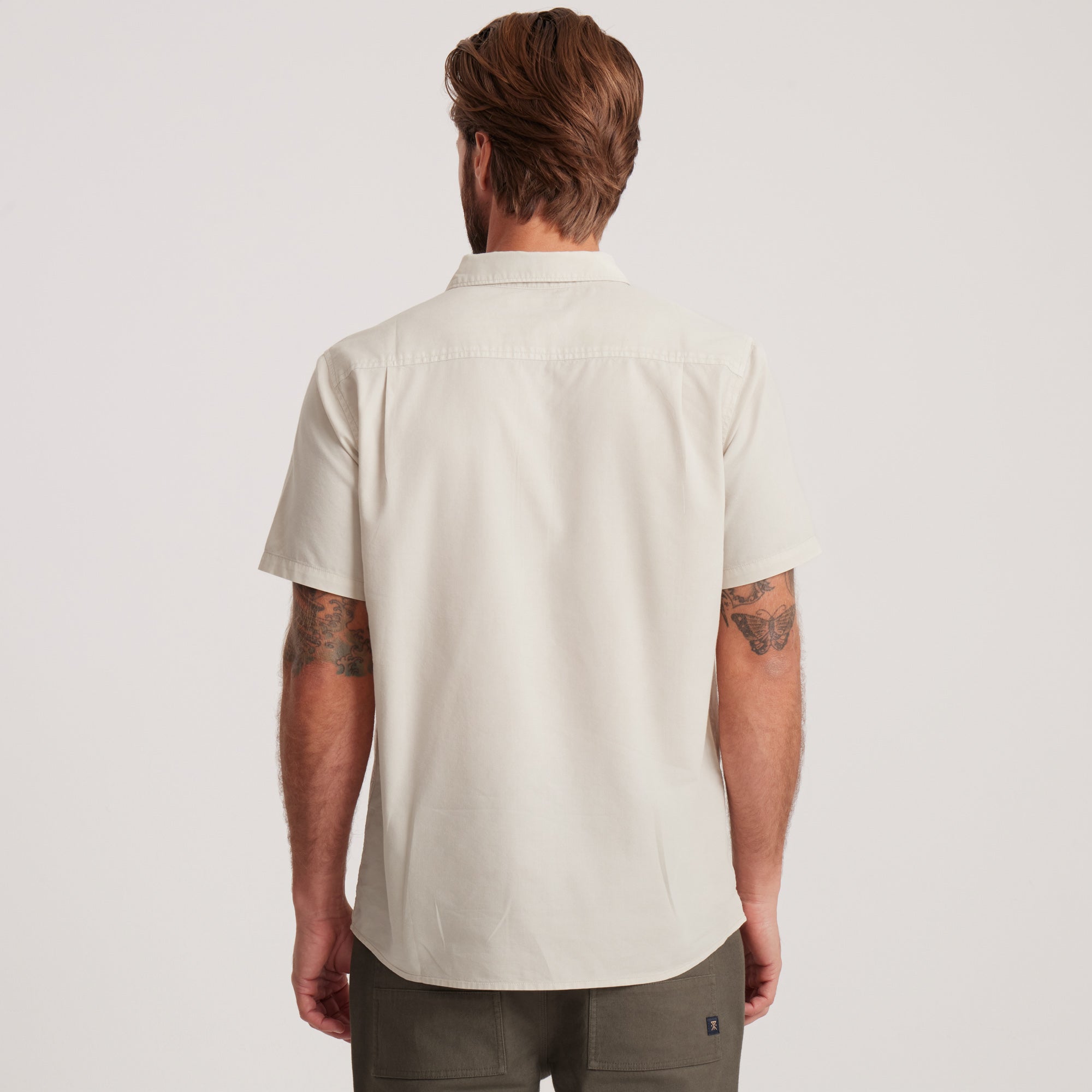 Back view of an off-white short-sleeve button-down shirt, highlighting its simple yet versatile design perfect for casual or semi-formal wear.