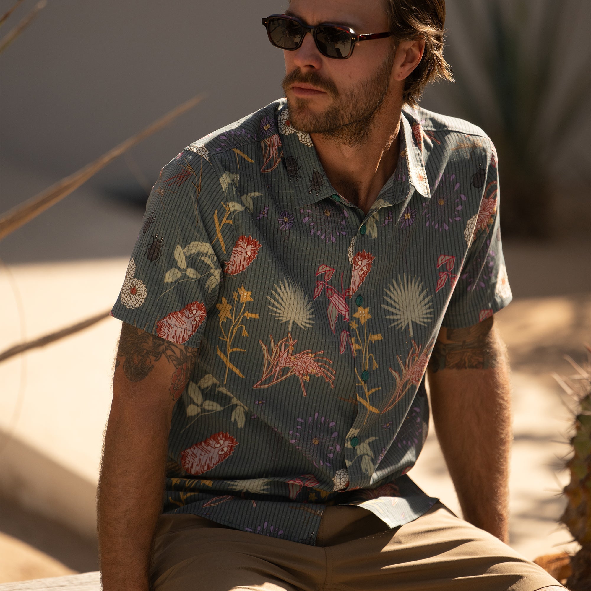 Close-up of a stylish outdoor adventure shirt featuring detailed sleeves, collar, and buttons, paired with a sun hat and fedora for a rugged, travel-ready look.