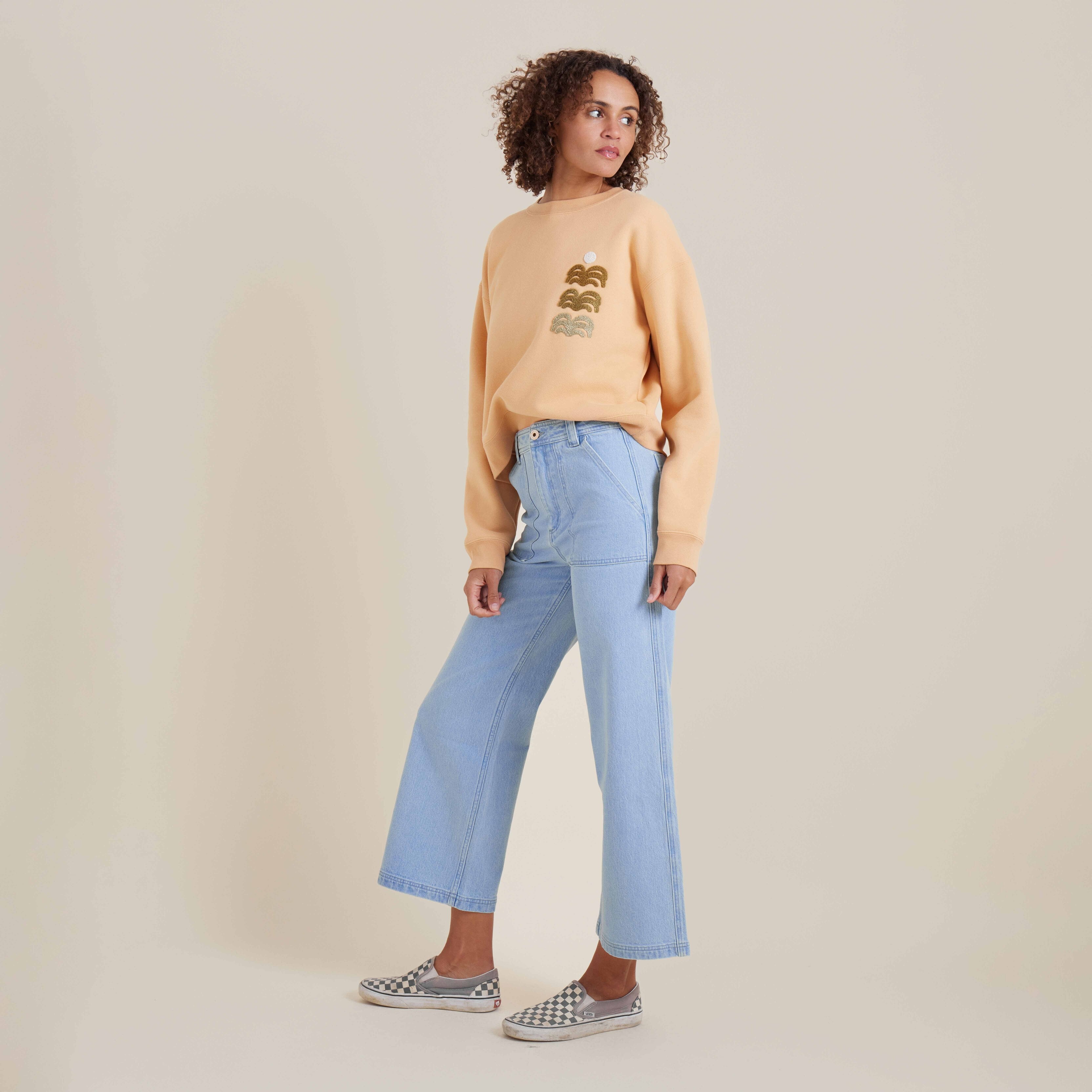 Model styled in a cozy light orange sweatshirt and denim wide-leg pants, ideal for everyday fashion and ultimate comfort.
