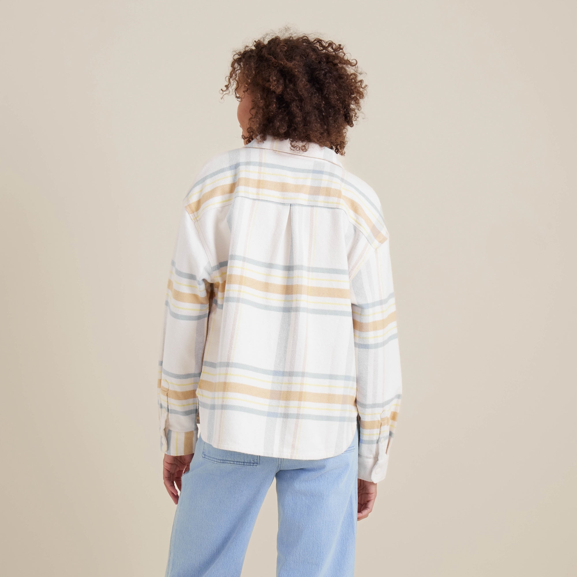 Back view of the Amberley Dusk plaid shirt by Roark, highlighting its relaxed fit and pastel-striped pattern. Perfect for layering during cool adventures.